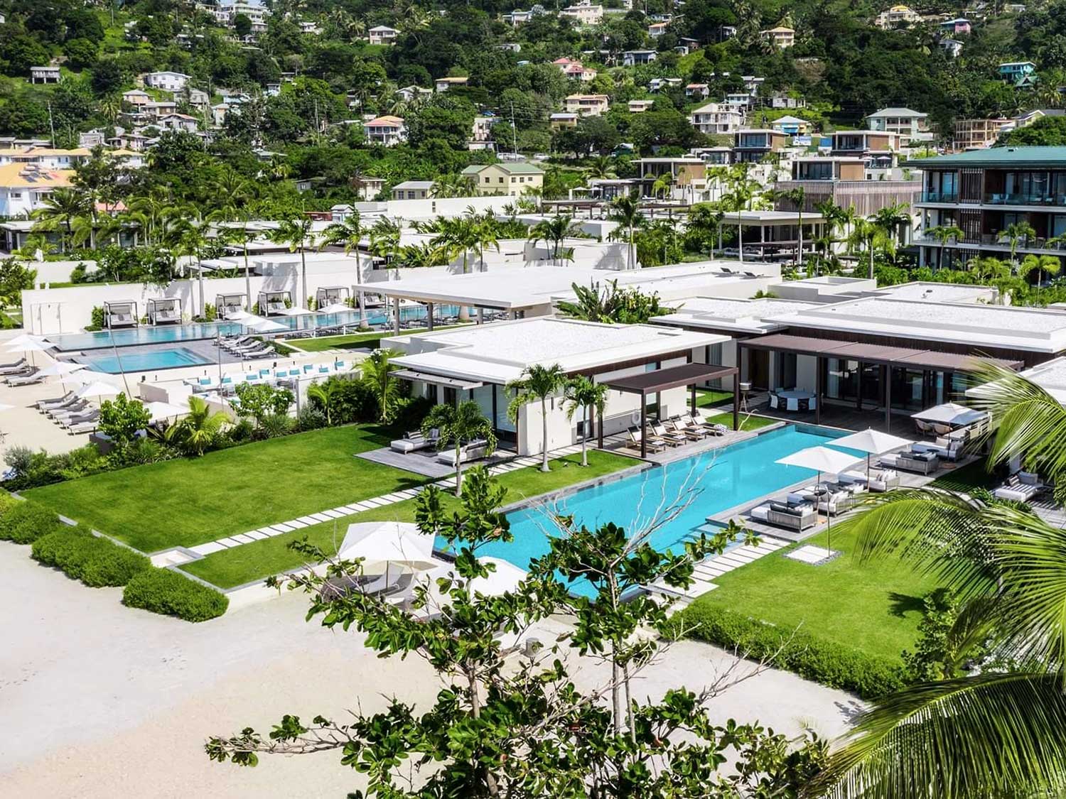 A pool next to a beach resort and the shore.