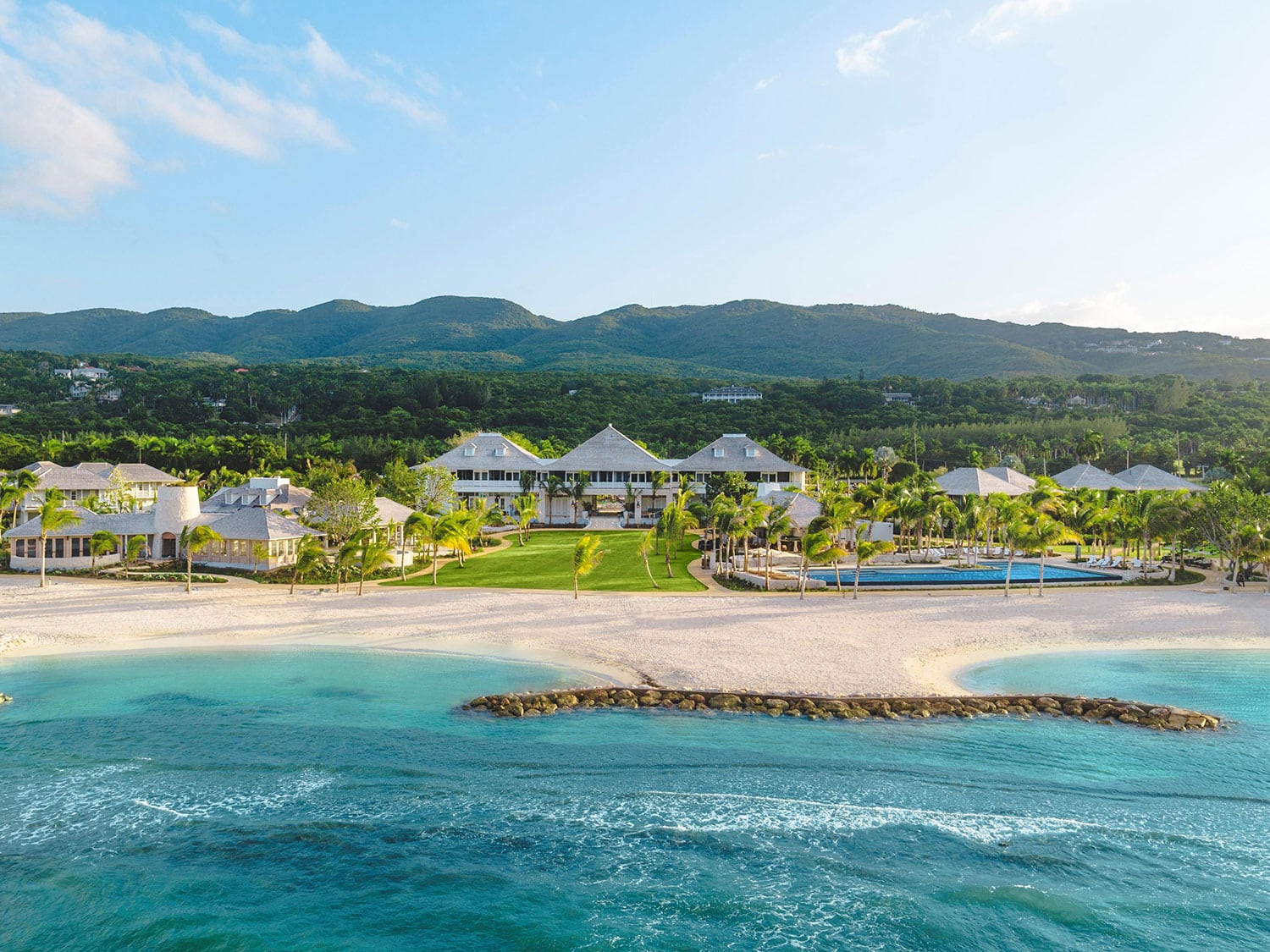 A string of resort buildings strung along a beach.