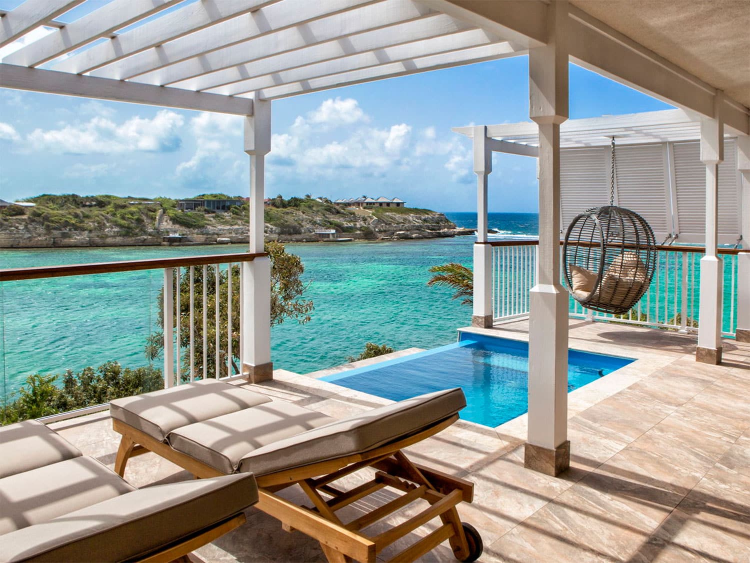 A luxurious pool, spa lounge deck by a pool and ocean.