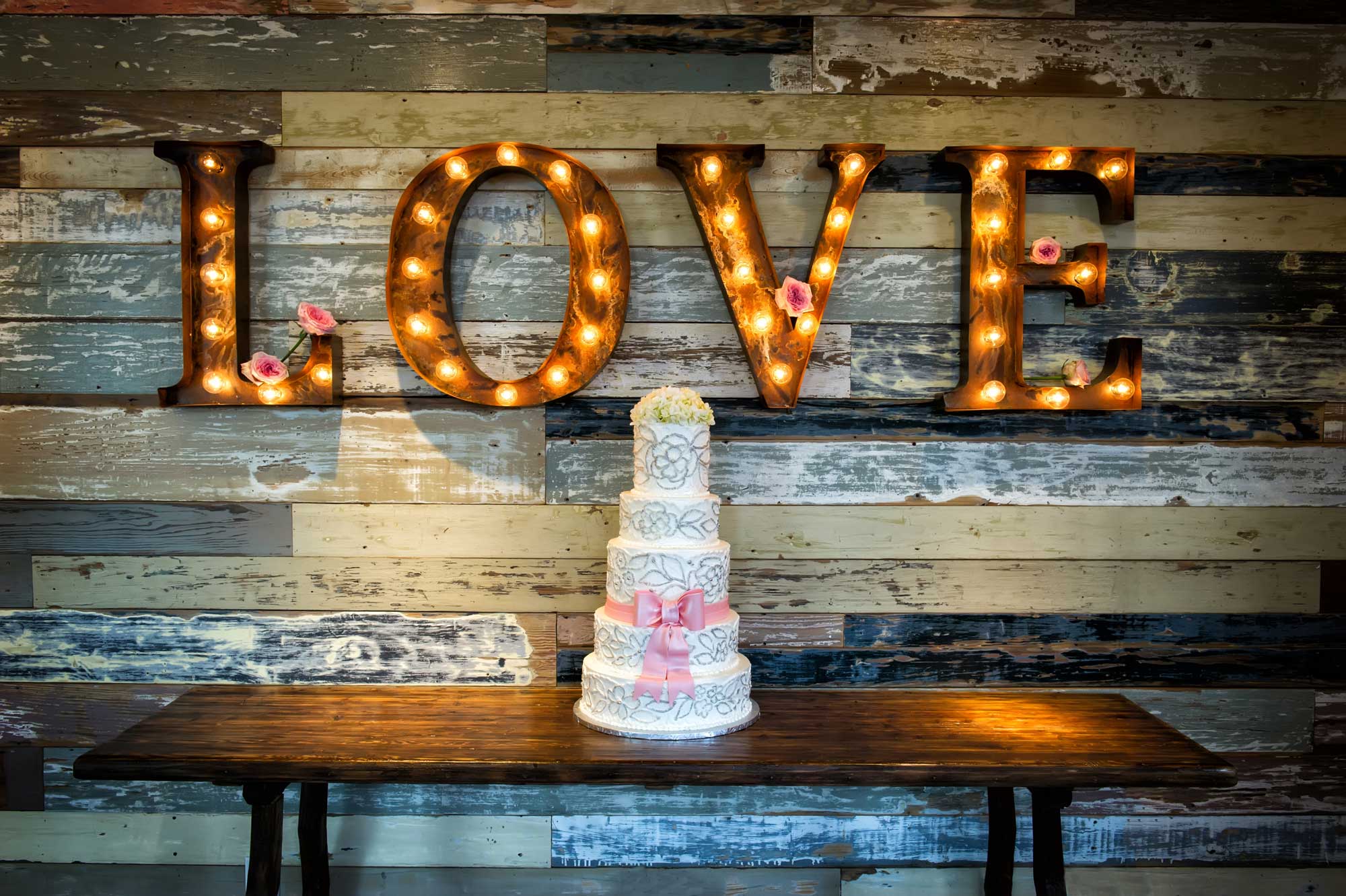 Tiered wedding cake with a LOVE sign in the background