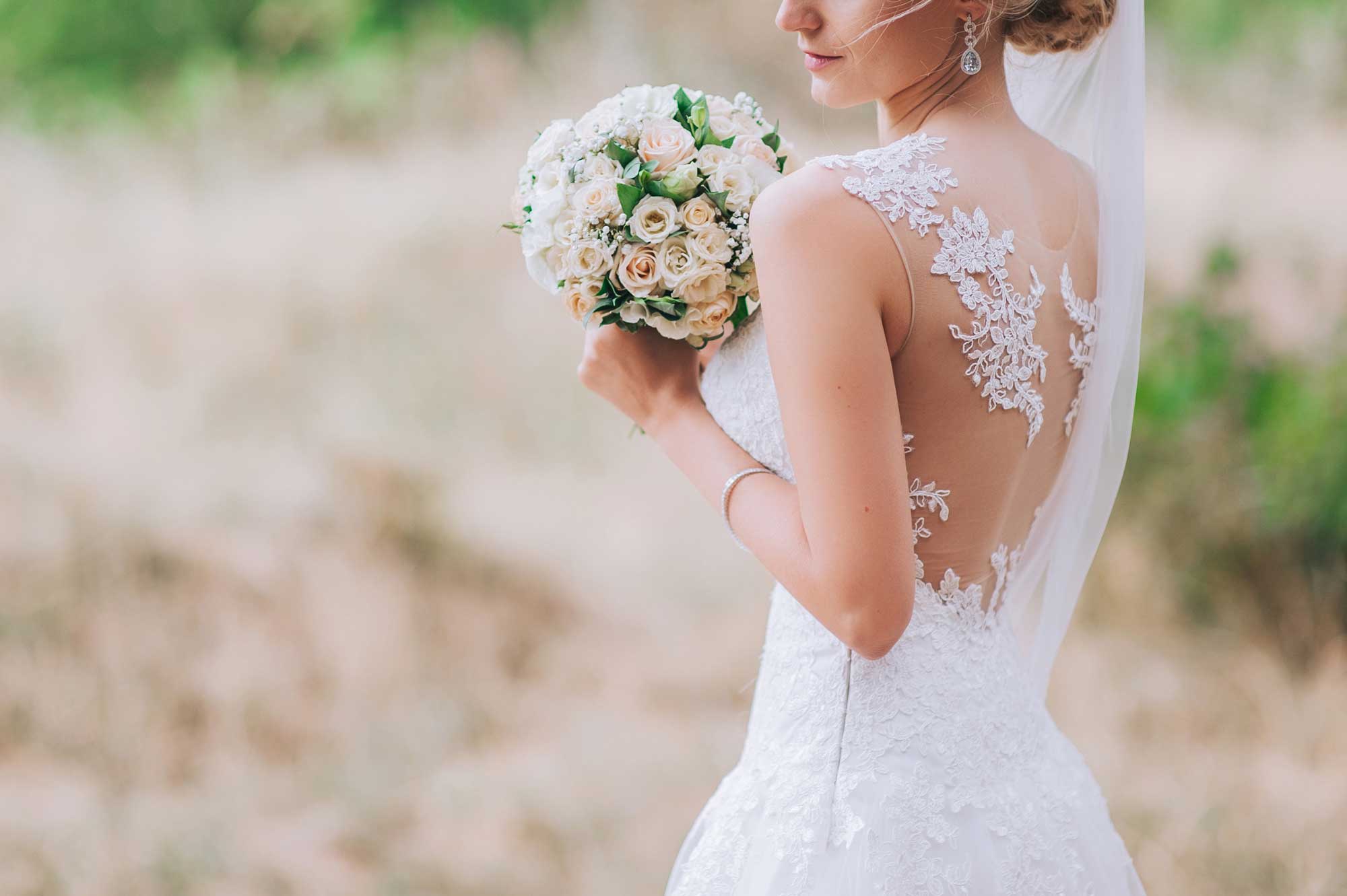 Bride in sleeveless wedding dress holding a white bouquet