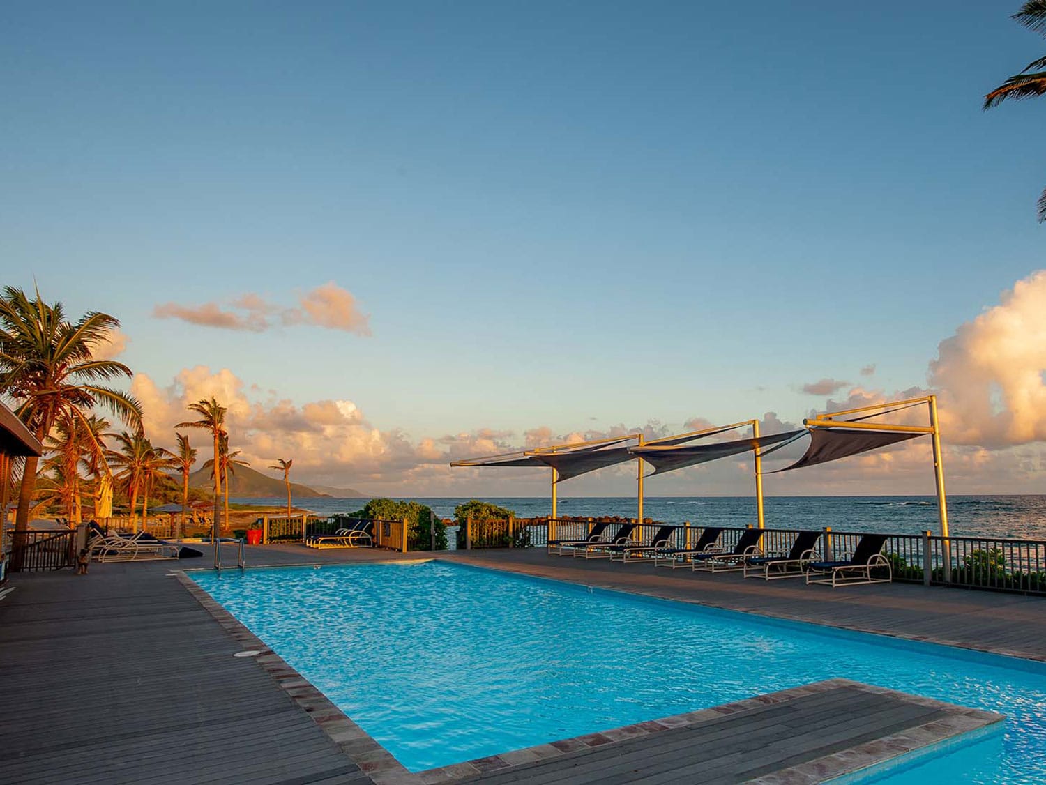 A pool next to the beach at sunset.