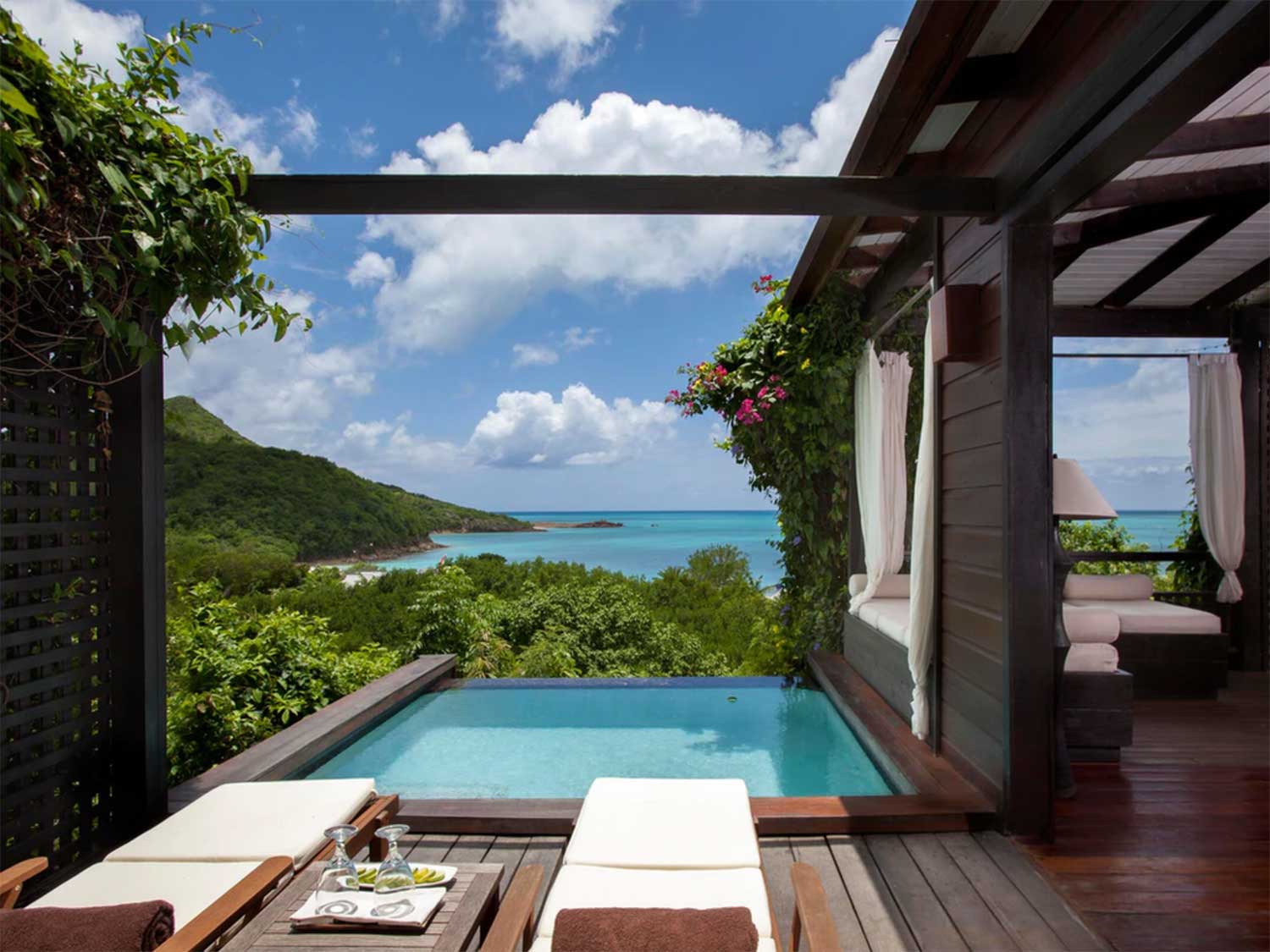 A single pool at a resort overlooking lush, tropical mountains and the ocean.