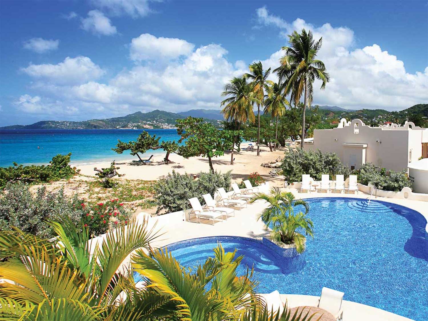 A resort pool next to a beach shoreline.