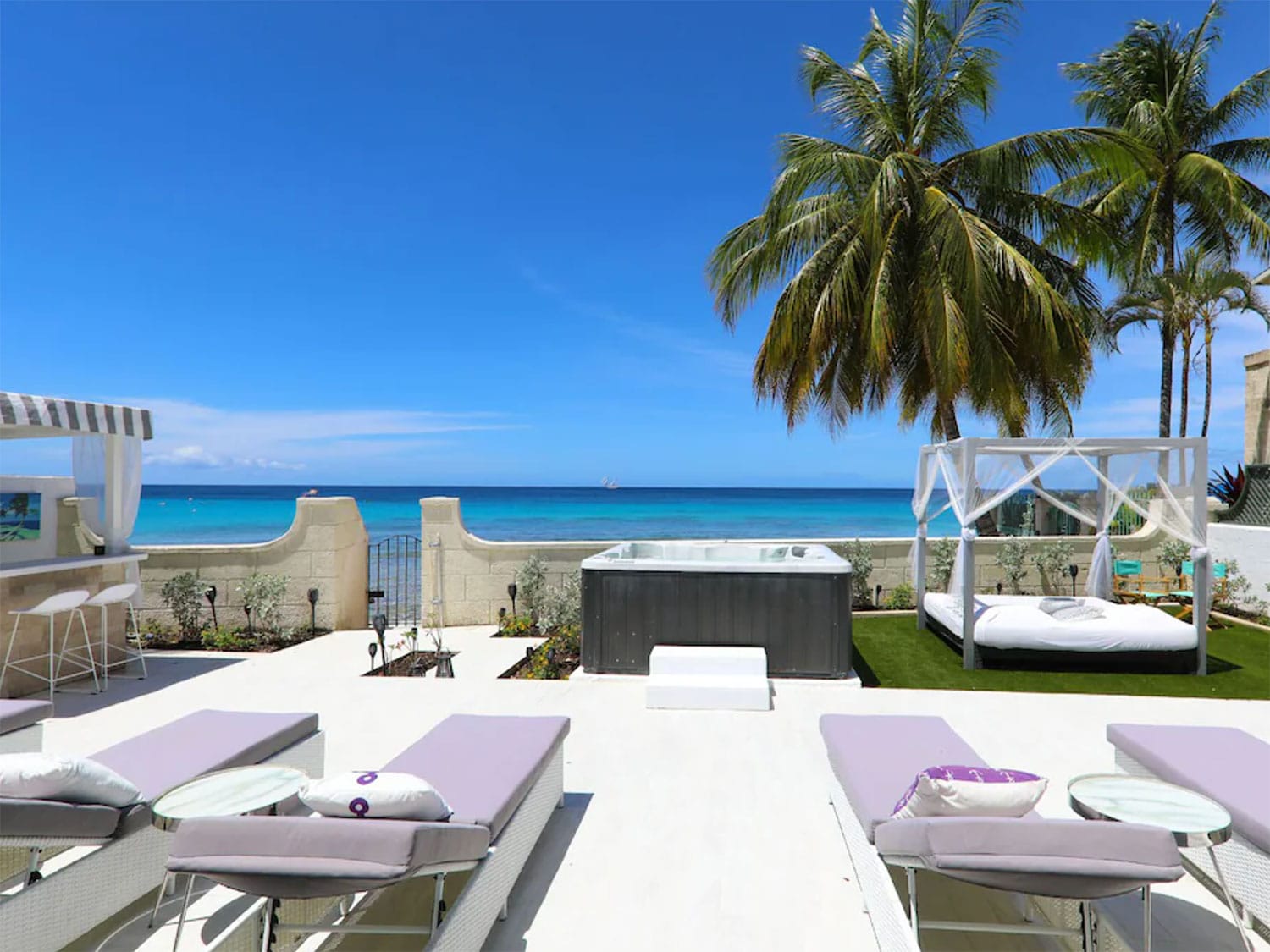 A jacuzzi next to an outdoor lounge area by the beach.