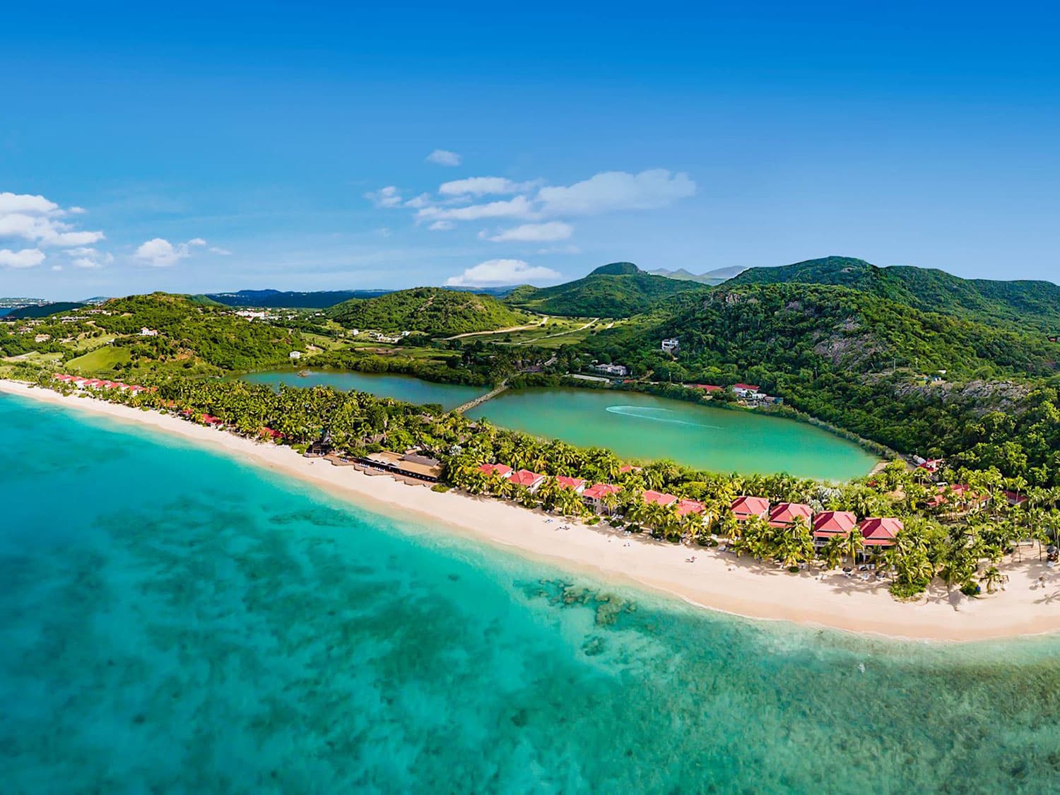 Aerial photo of a beach resort strung along the shores of a beautiful, blue/green crystal clear ocean.