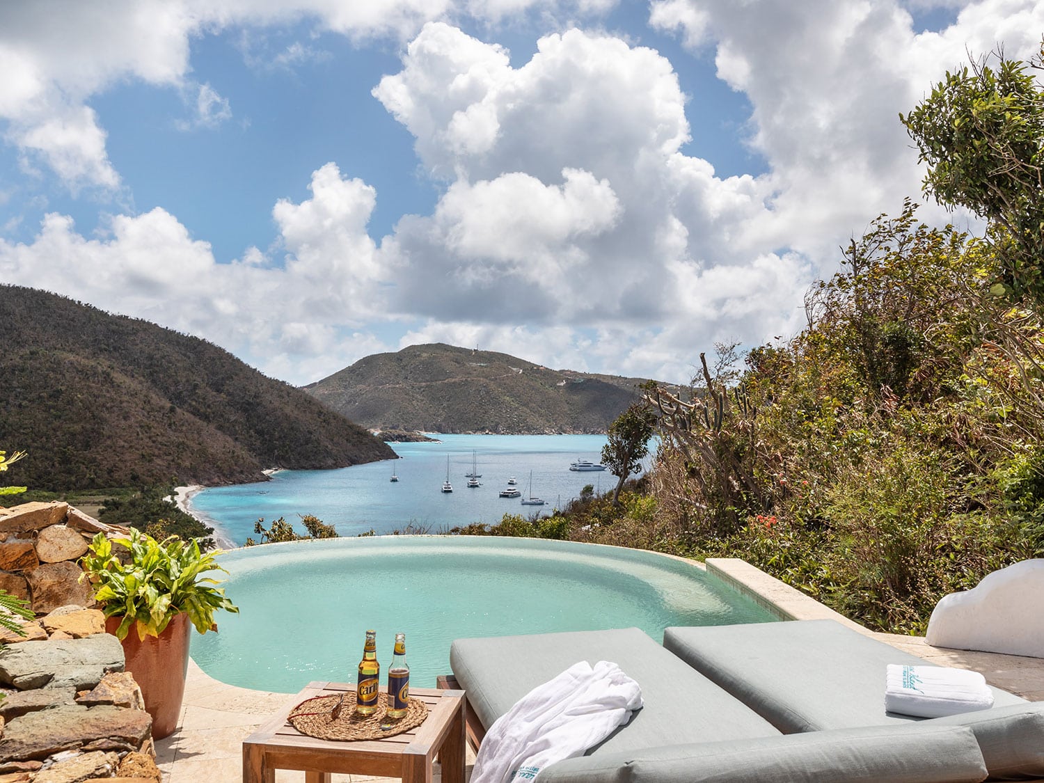 A pool and lounge chairs overlooking the bay of the ocean.