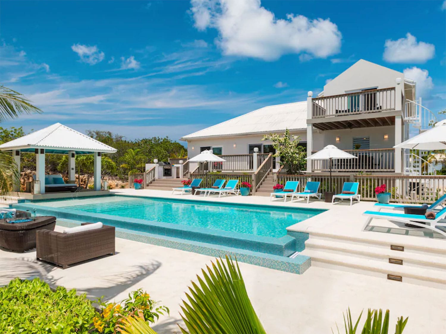 An outdoor pool and lounge area by a resort-style home.