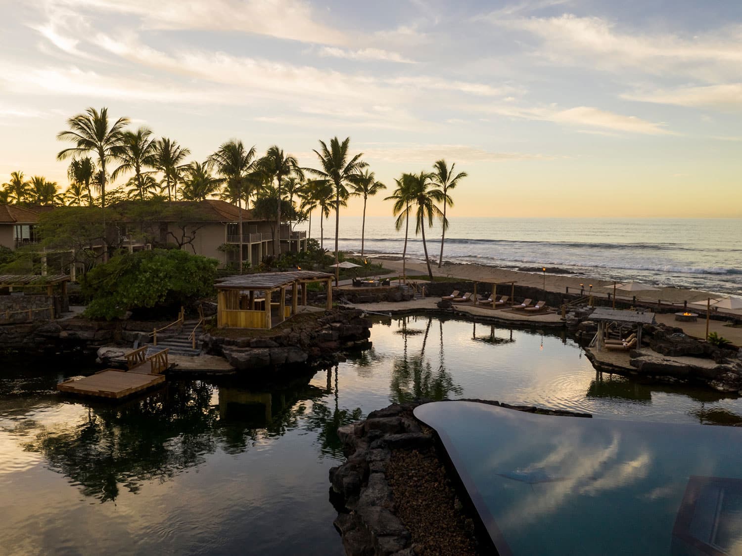 View overlooking a pond, swimming pool, and beach resort at Four Seasons Hualalai.