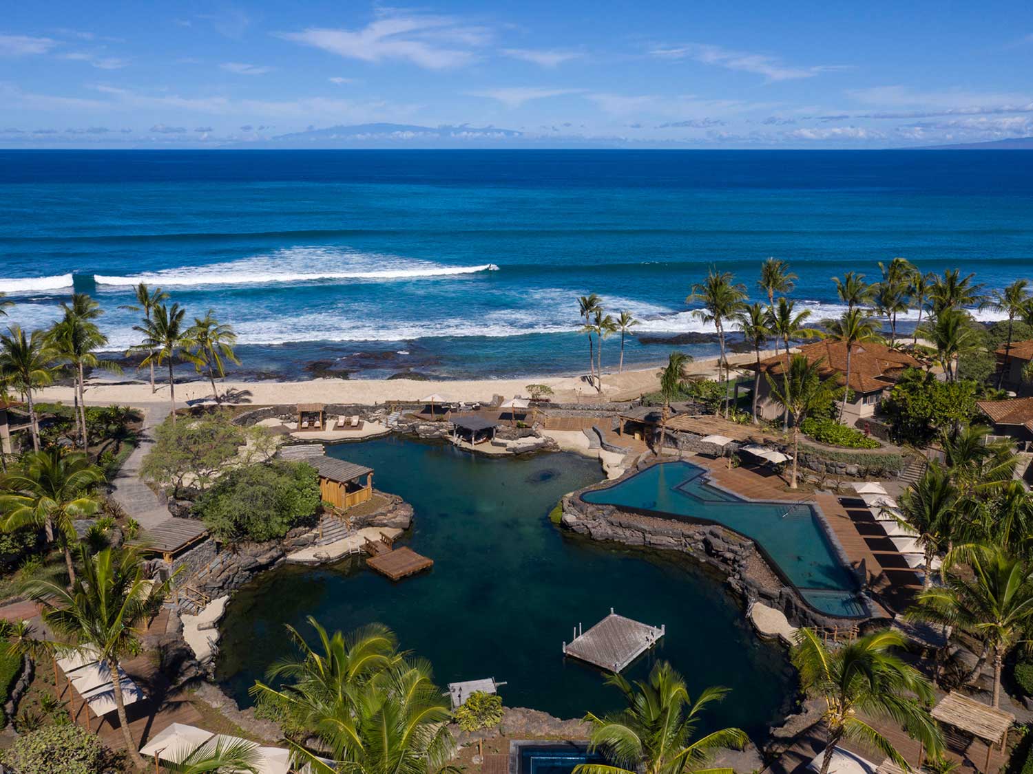 View overlooking a pond, swimming pool, and beach resort at Four Seasons Hualalai.