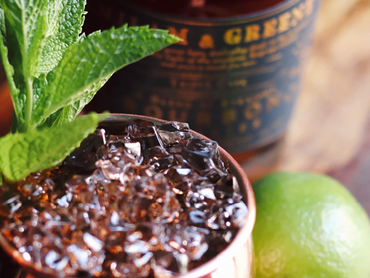 A mule cocktail cup with beverage next to a bottle of liquor.