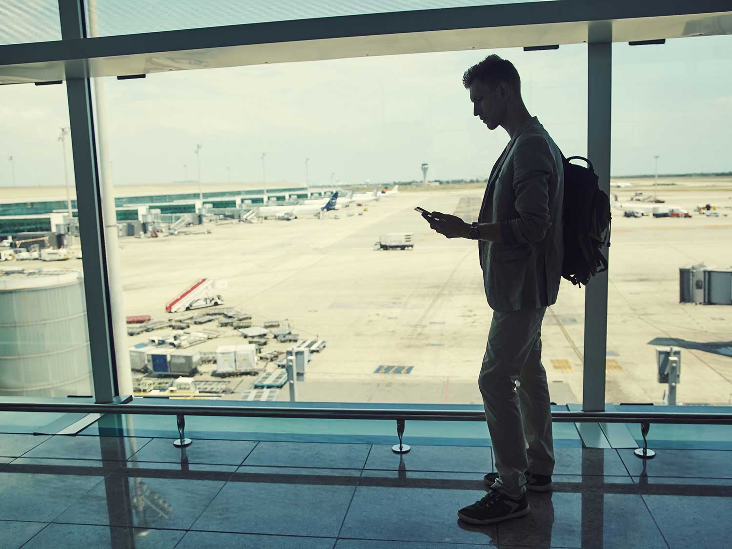 Man carrying backpack at airport while waiting for plane.