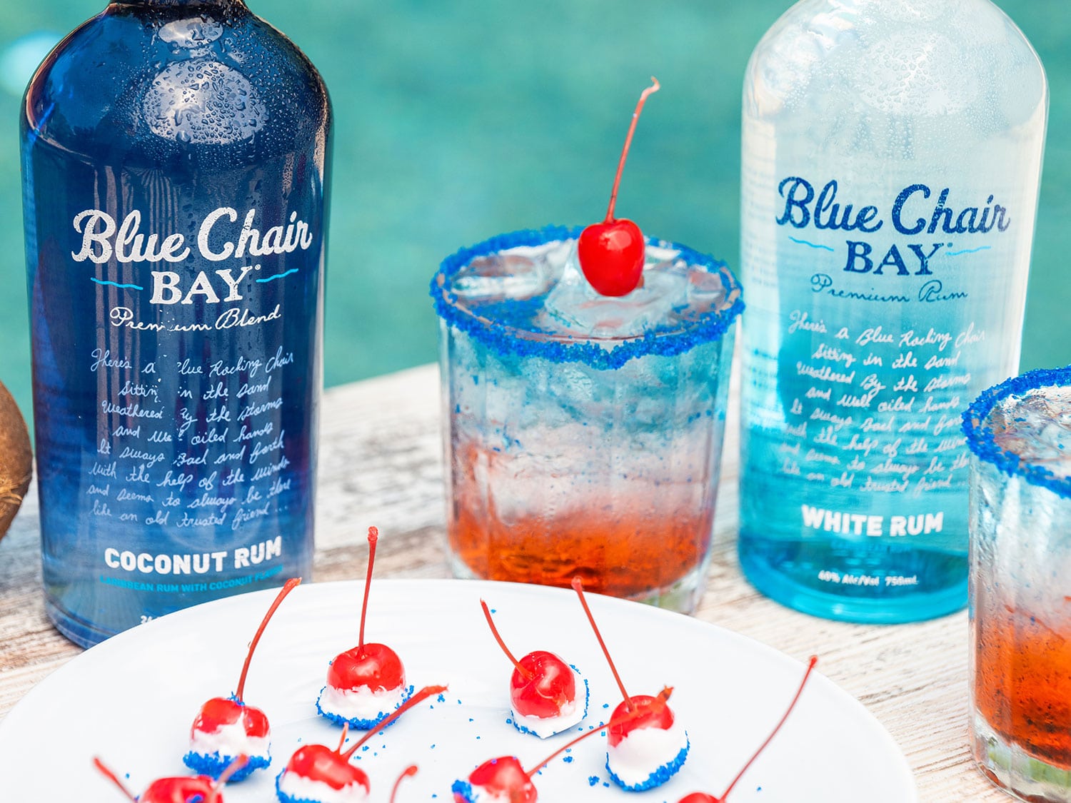 A red, white, and blue cocktail on a table with Blue Chair Bay cocktails.