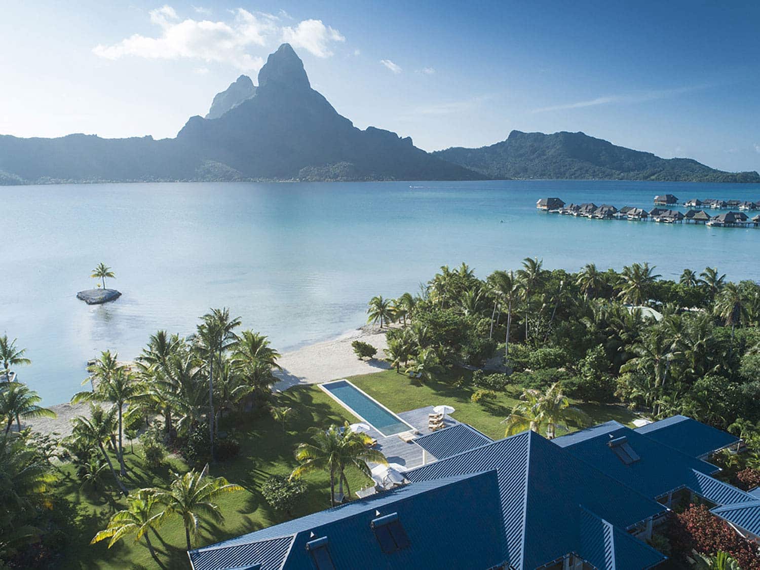 An aerial view of Bora Bora One resort overlooking the ocean and a mountainous island in the distance.