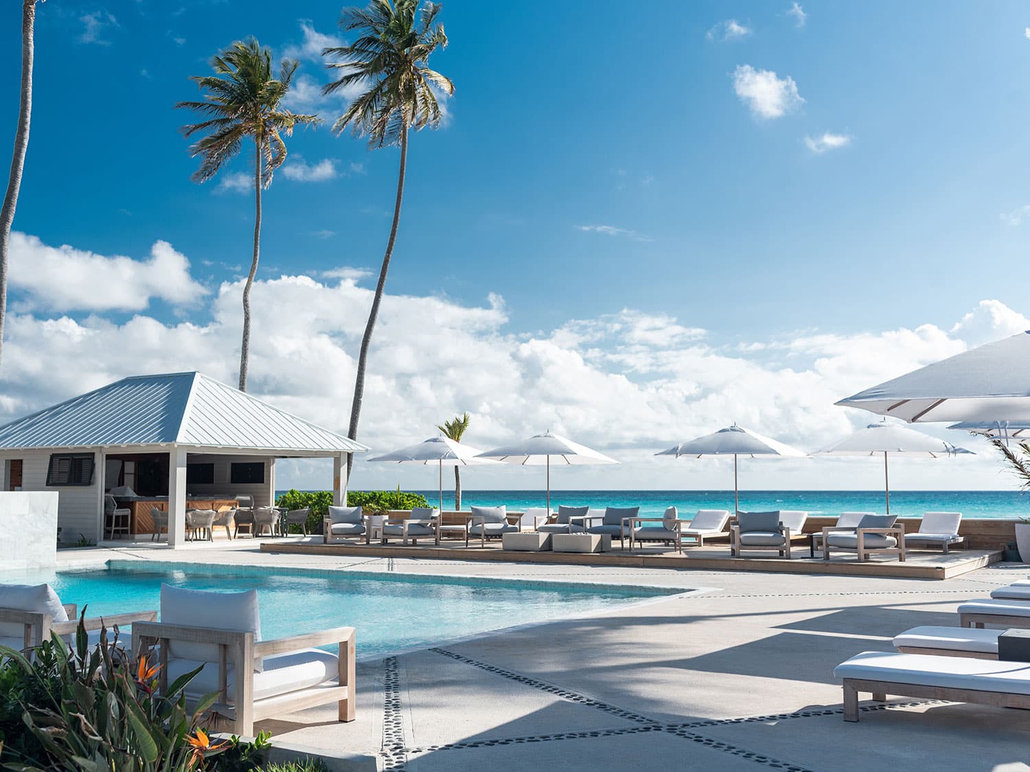 A pool and lounge area with the ocean in the background.