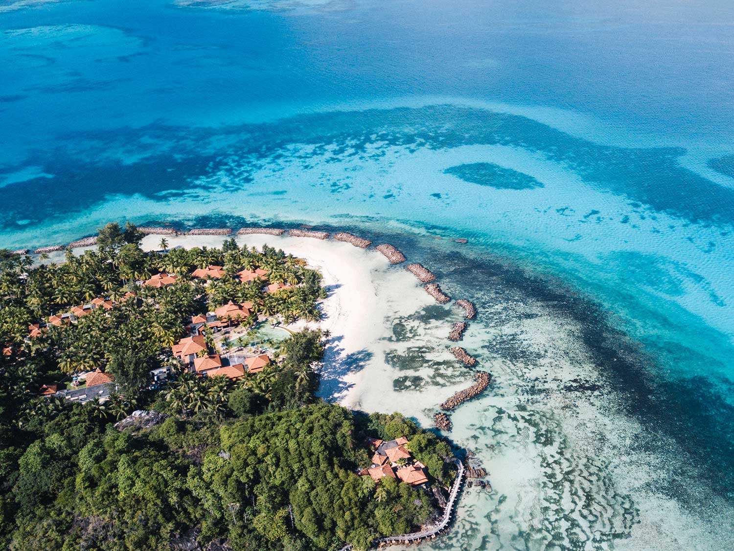 An aerial photo of an island beach resort by the ocean.