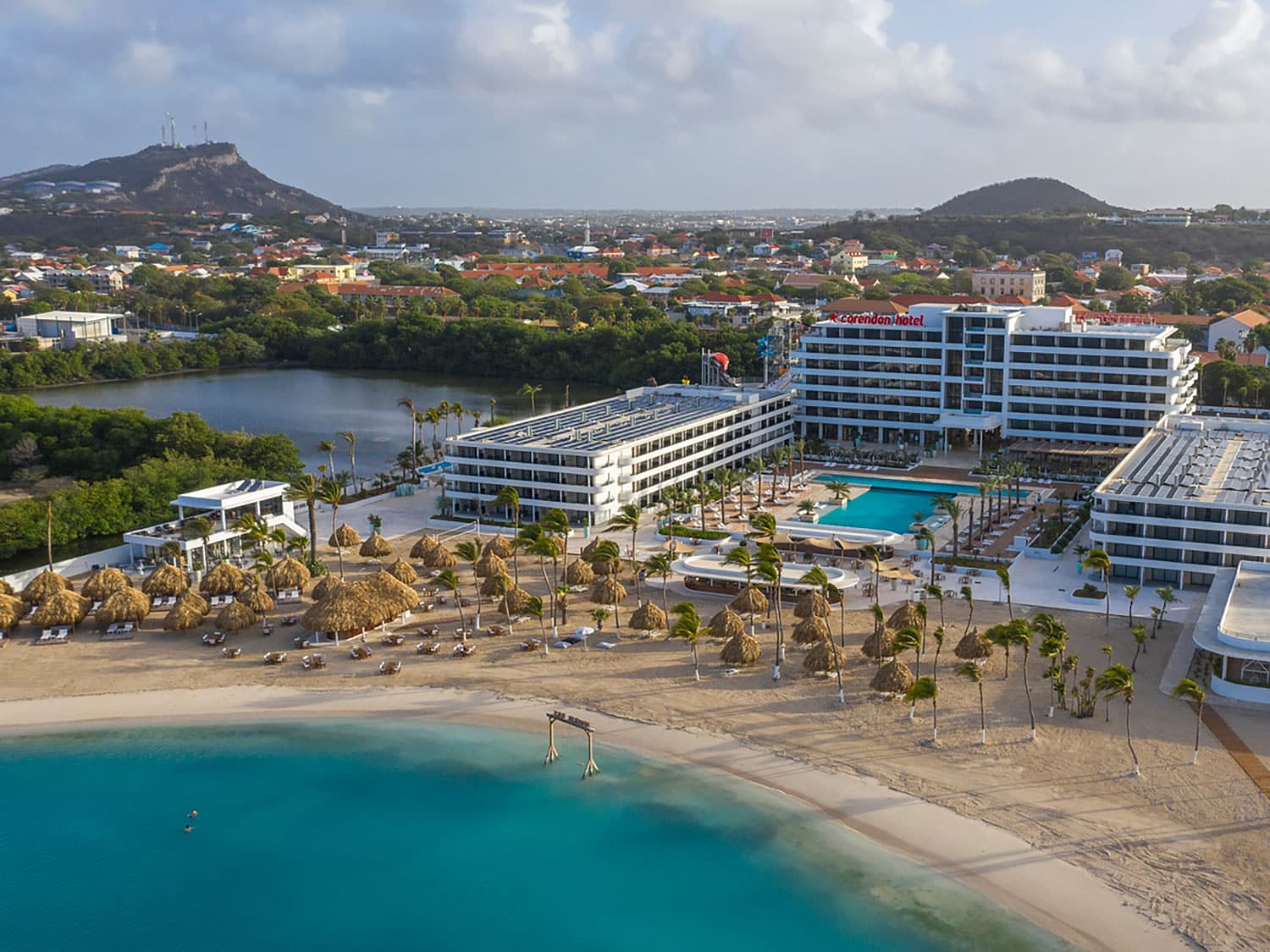 Aerial view of a beach resort next to a beach covered in palms.