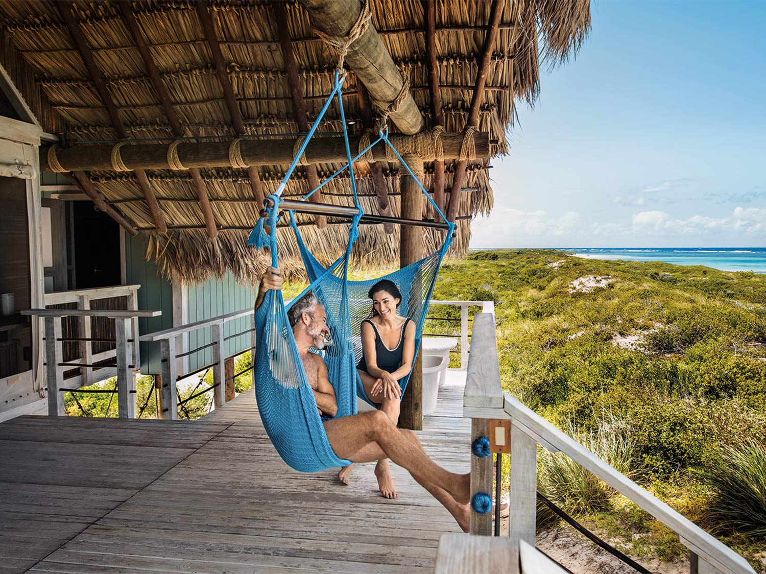 Two people sit in hammocks at a beach resort of the island of Anegada.