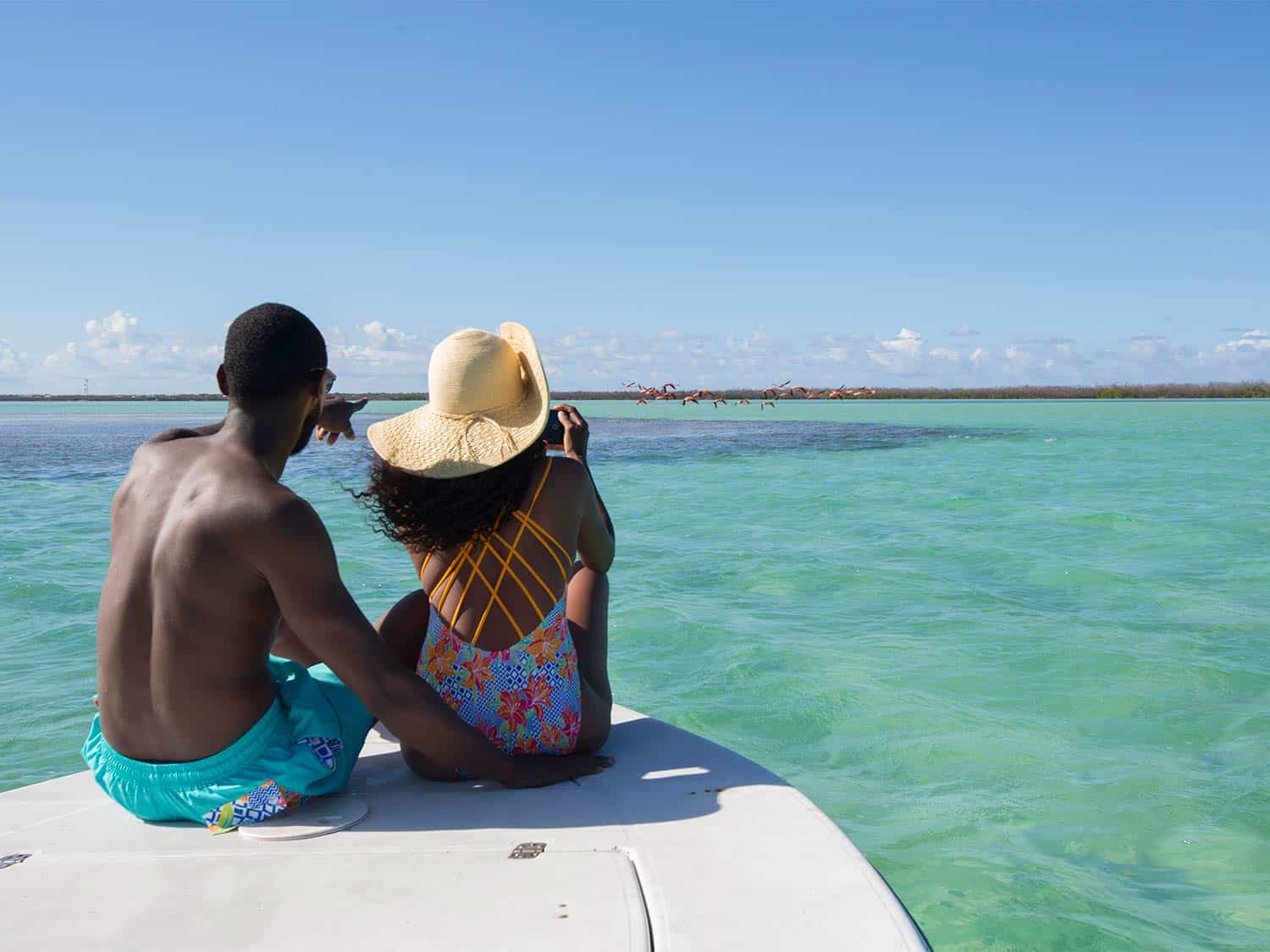 A couple sits on the front of a catamaran on the ocean.