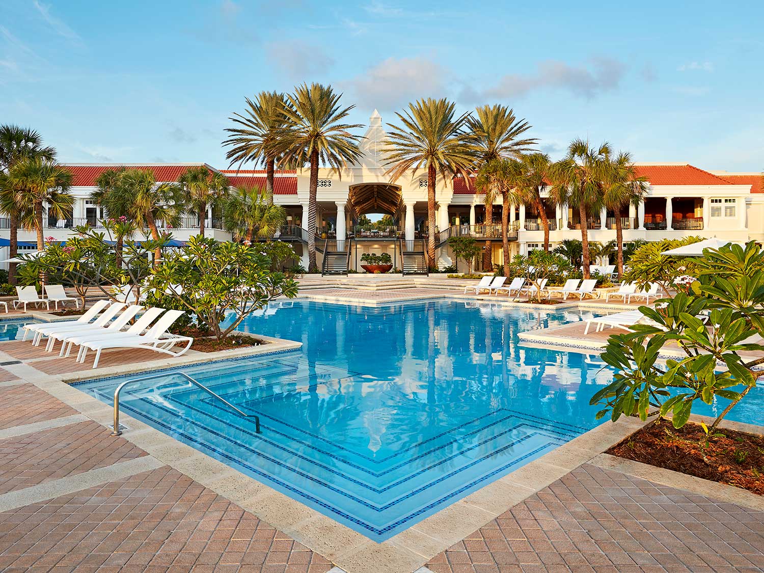 An outdoor pool at a resort, surrounded by lounge chairs.