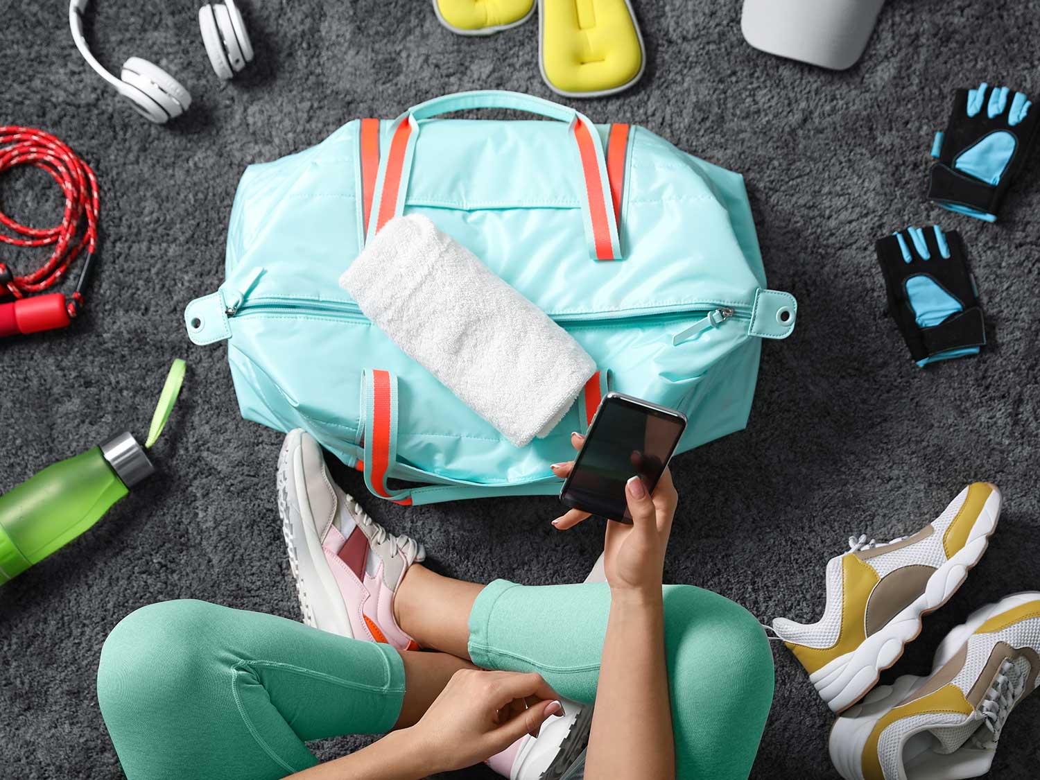 Woman sitting on the floor with fitness bag and equipment.