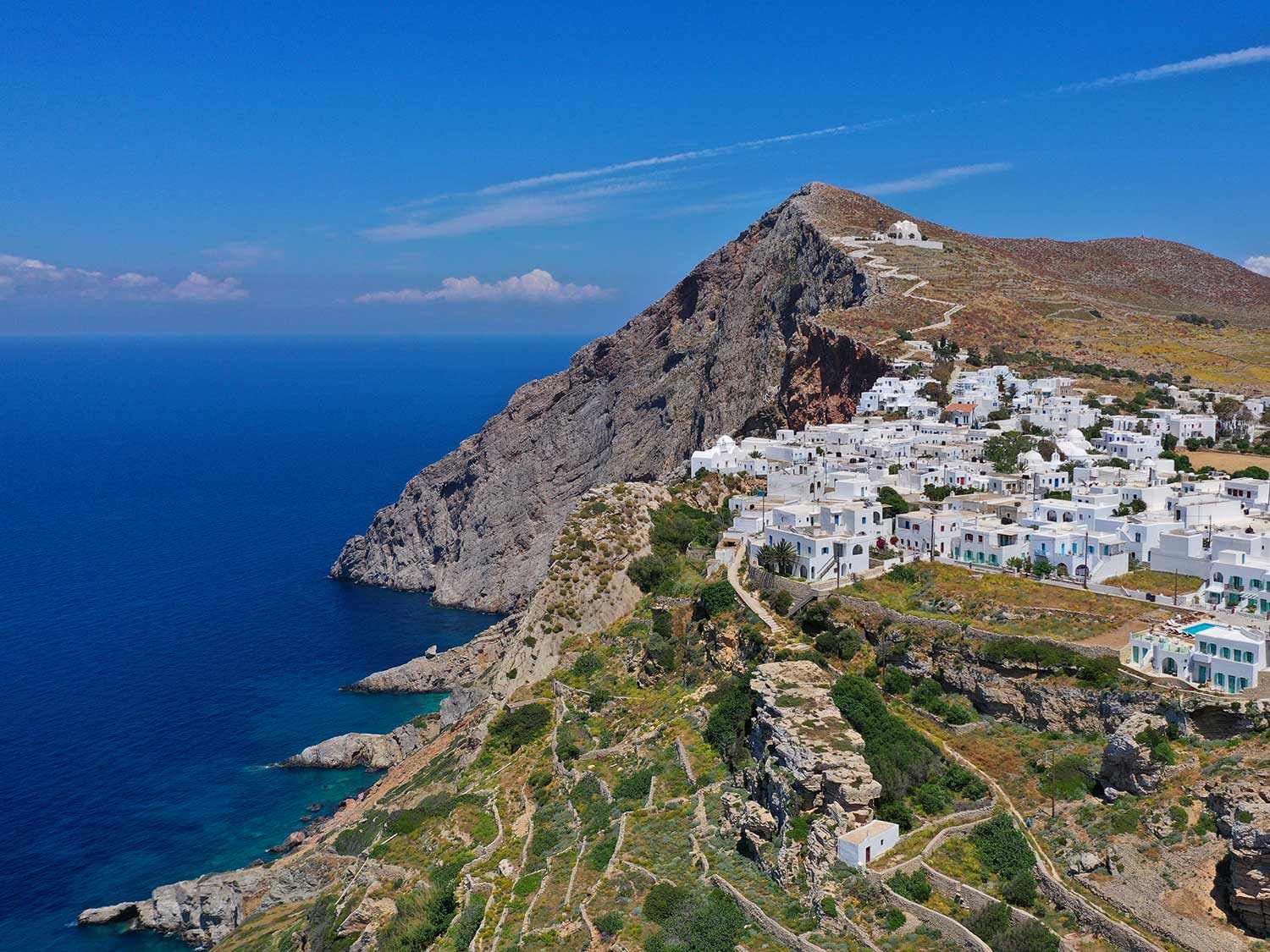 A hillside Grecian town of white buildings with blue shutters.