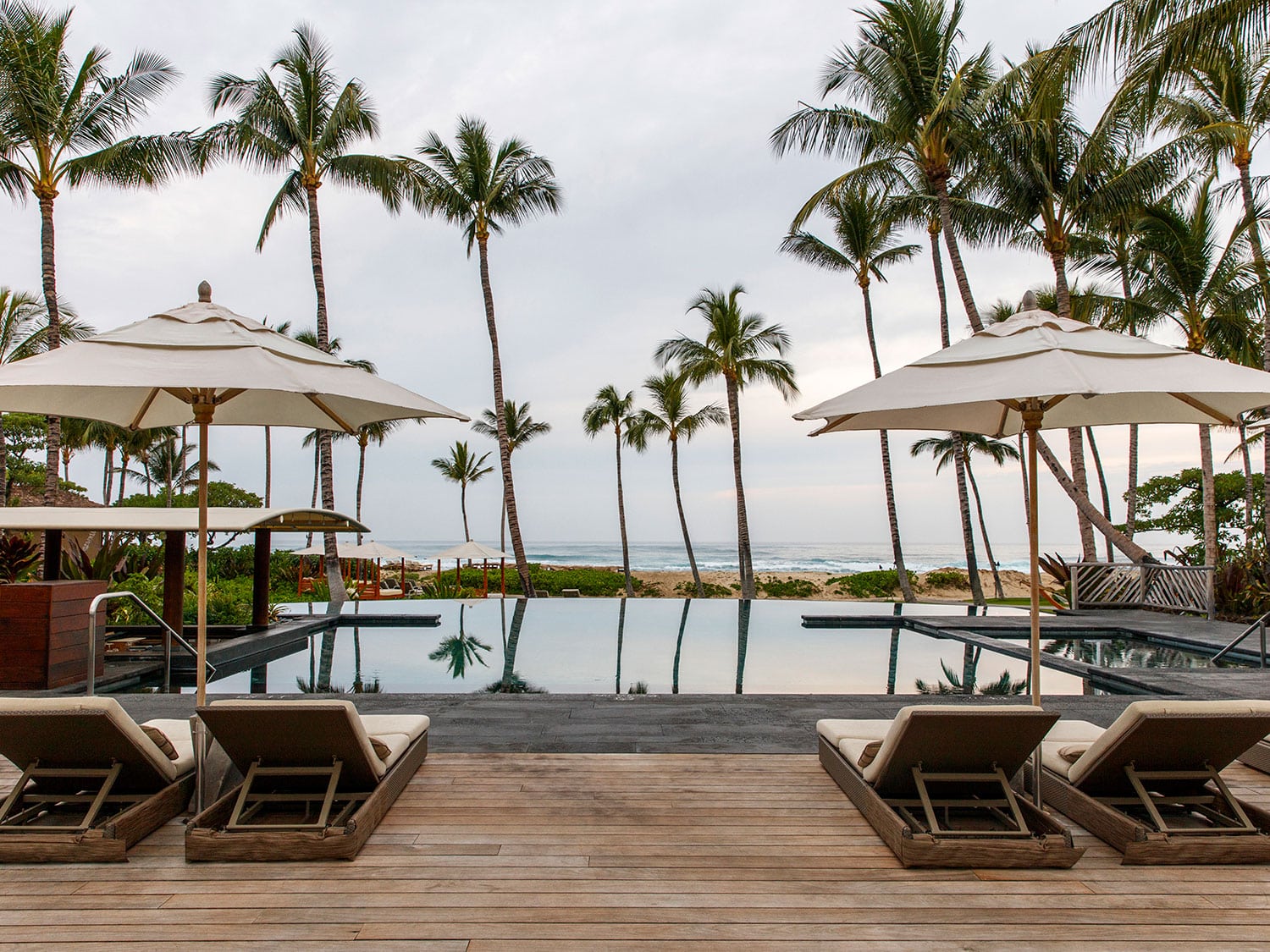 Lounge chairs beside an oceanside resort pool.