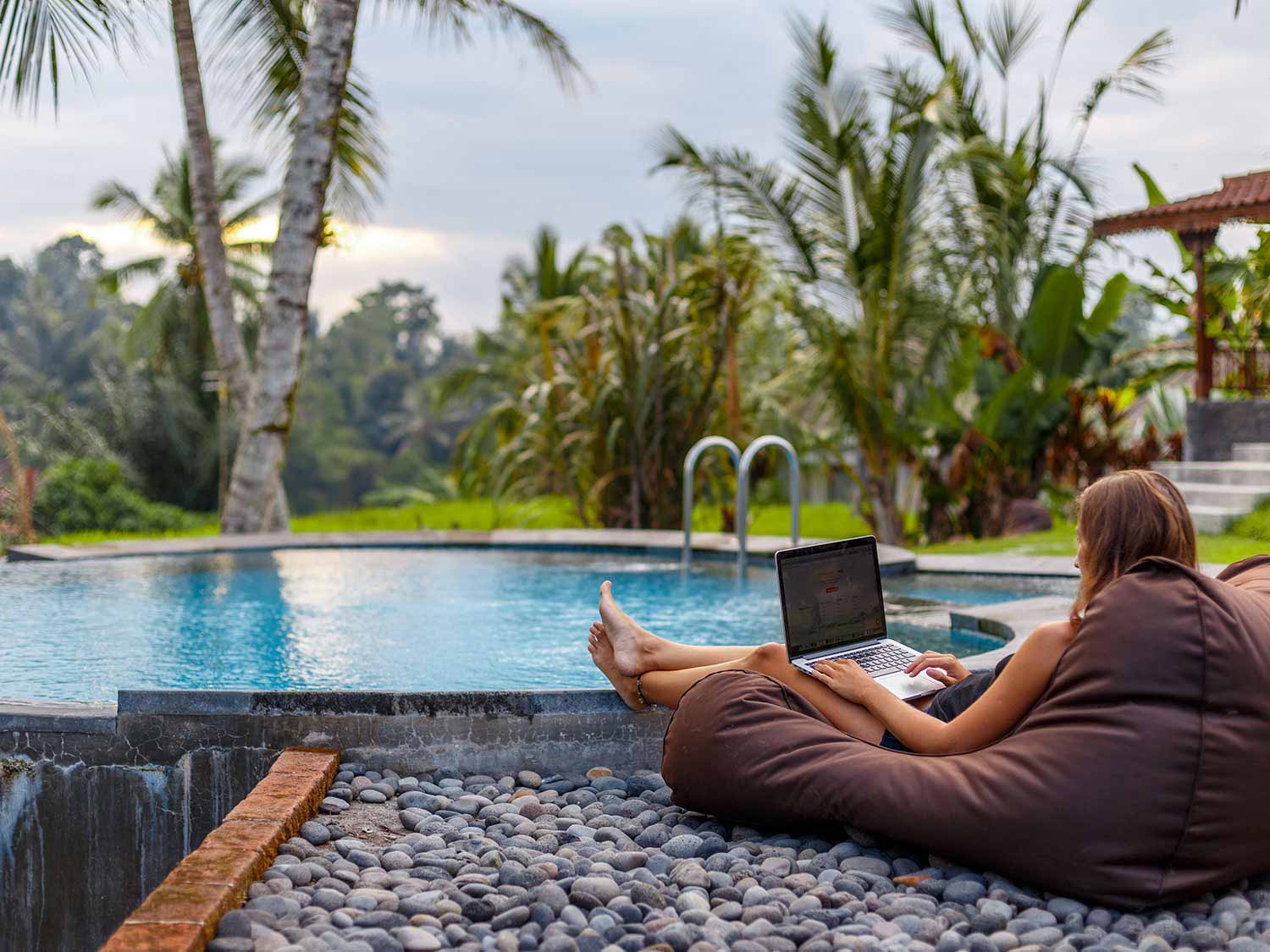 Person using a laptop by a swimming pool