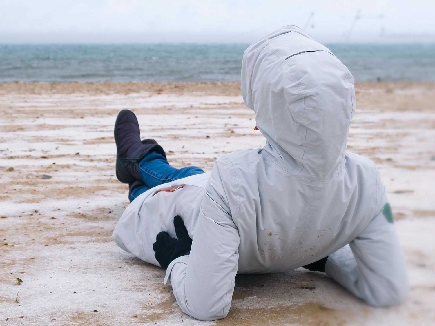 Person resting on the beach wearing a jacket