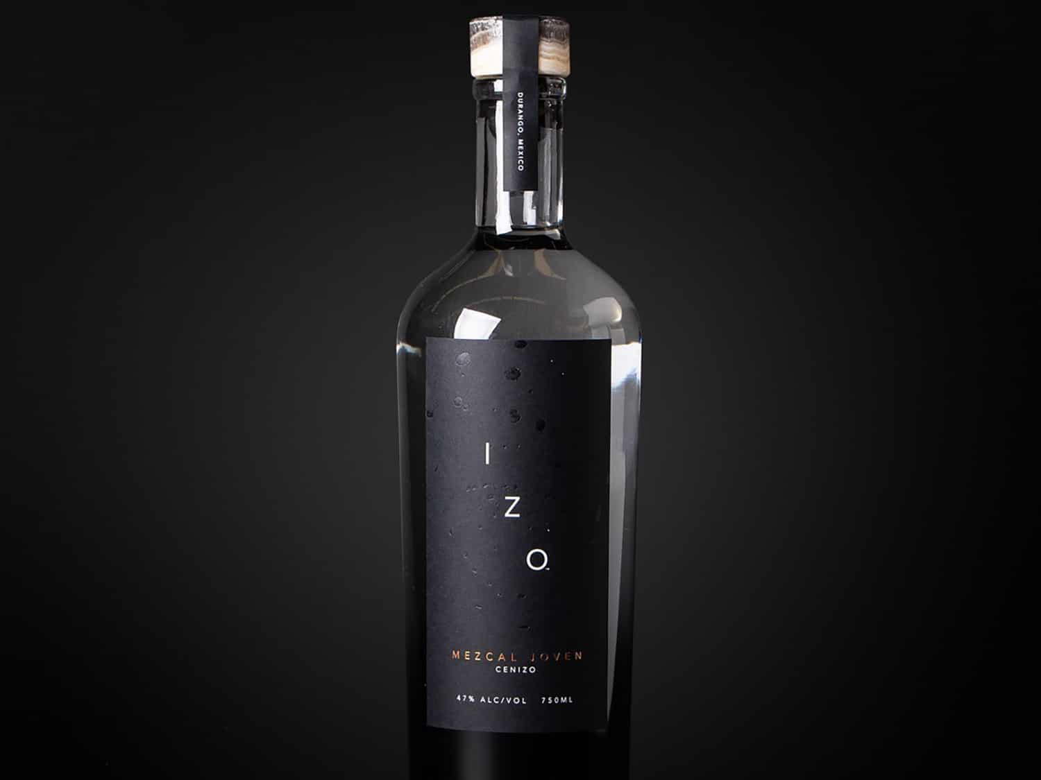 A bottle of IZO Mezcal on a black background.