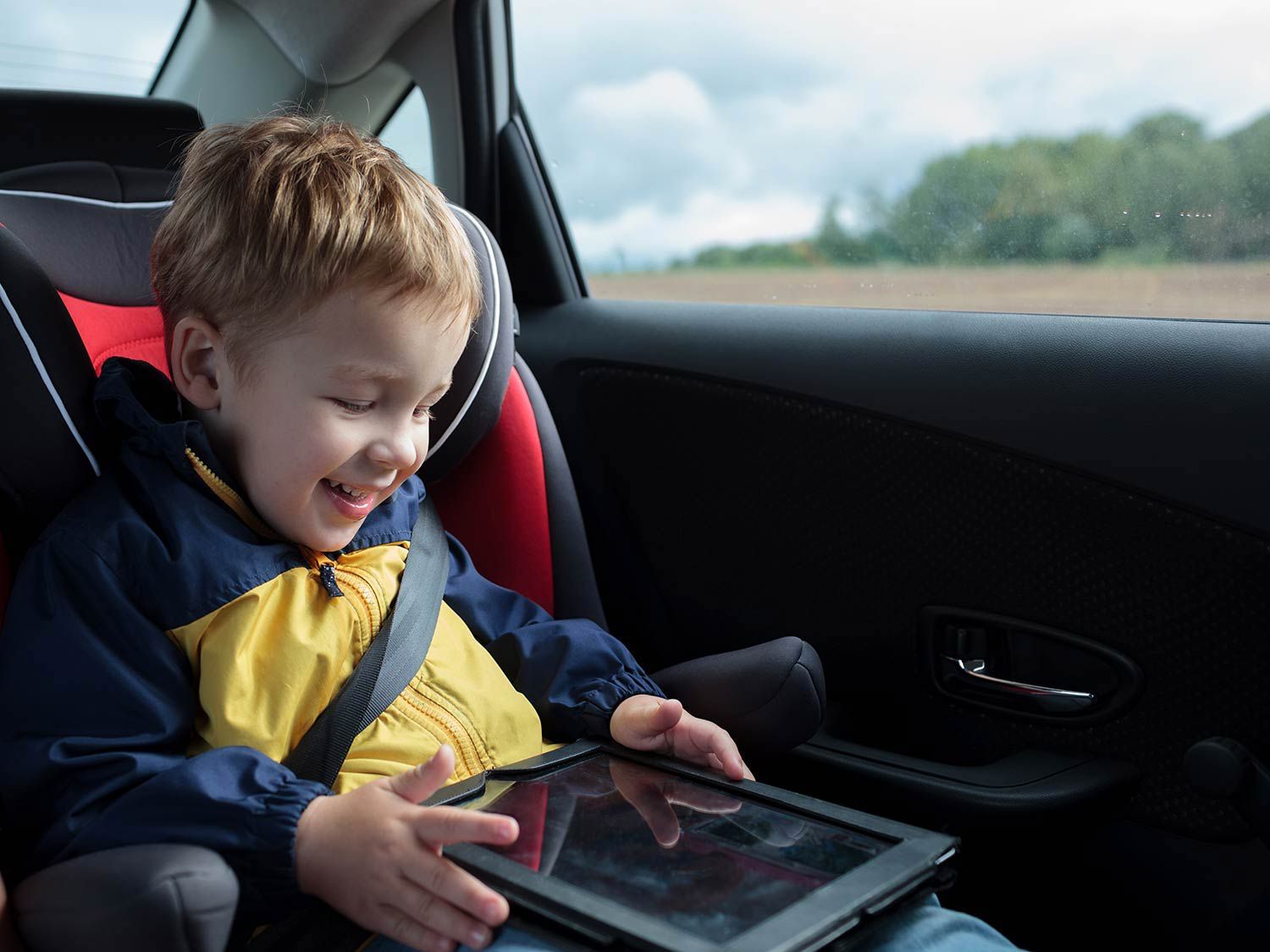 Kid playing with a tablet in a car.