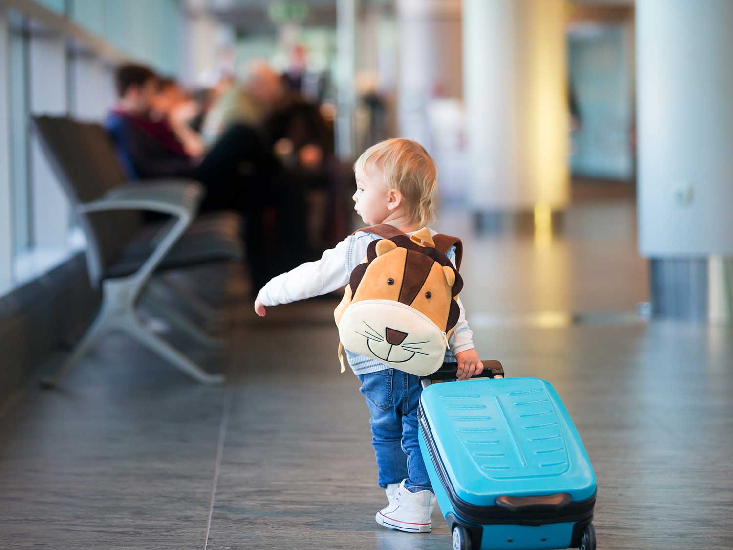 A child carrying luggage through an airport.