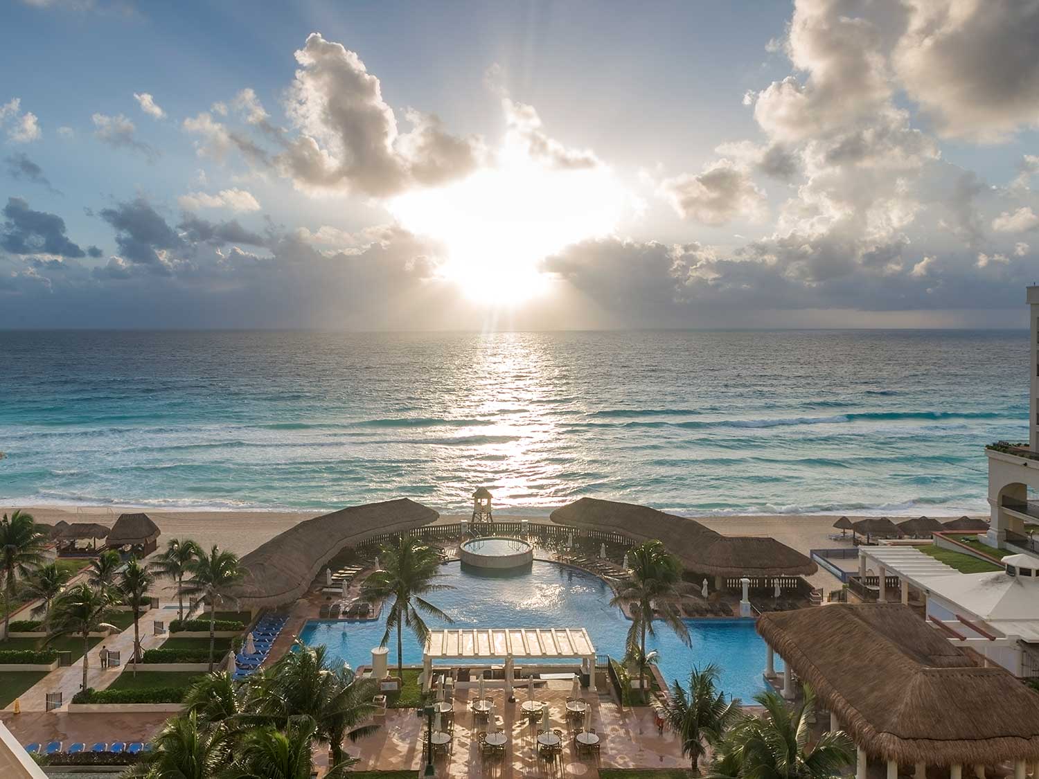 Aerial photo of the sunset against the waves of the ocean beside a beach resort.