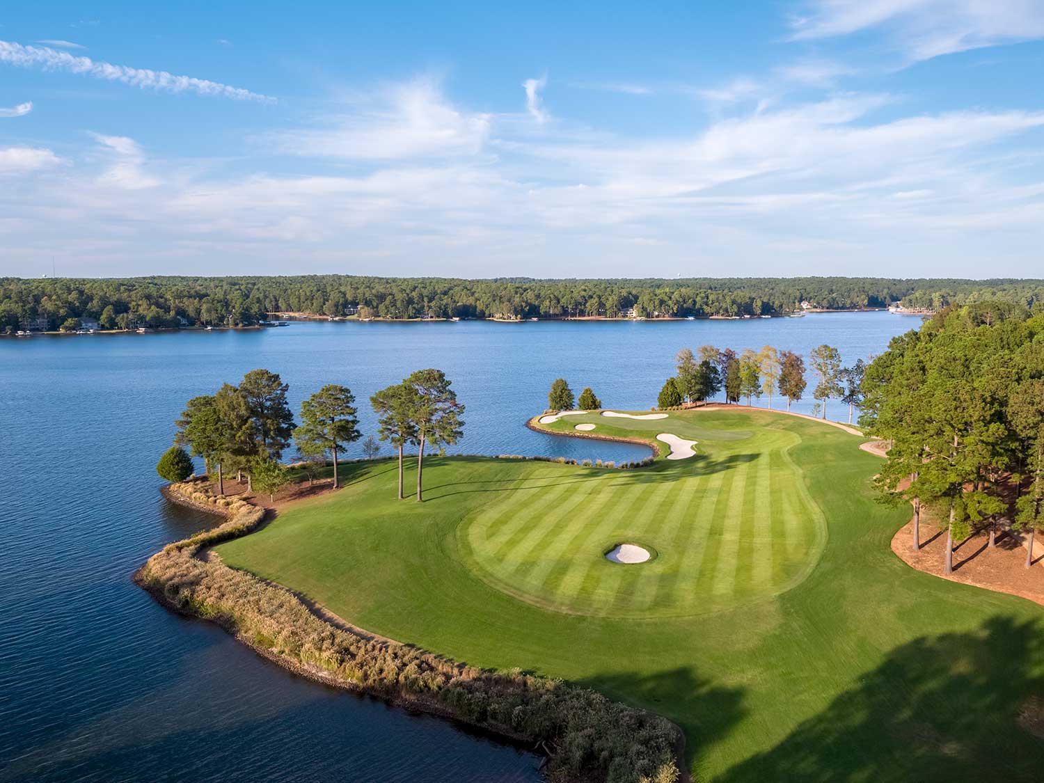 An aerial view of a golfing green course by a river.