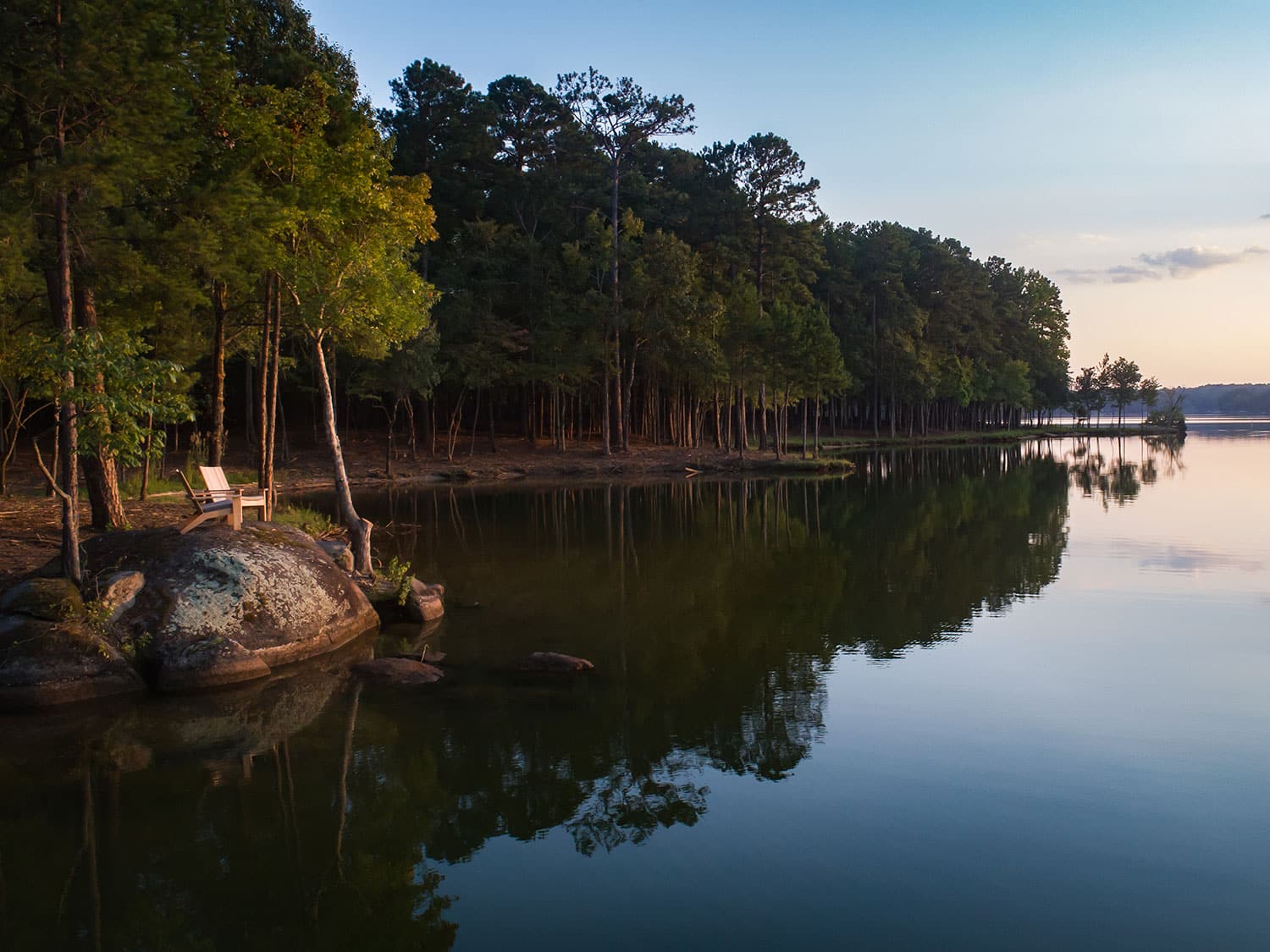 A pair of chairs next to one of the bodies of water in Reynolds Lake Oconee, at sunset.