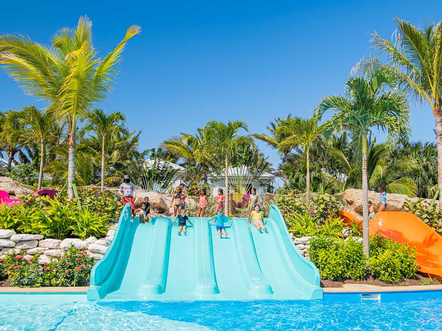 Kids sliding down a water slide at a beach-side resort water park.