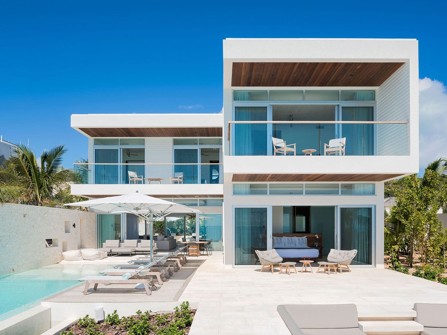 A small resort-style house next to a pool and lounge area.