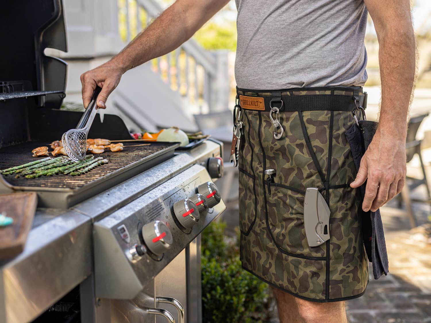 A man wearing the GrillKilt apron while grilling.