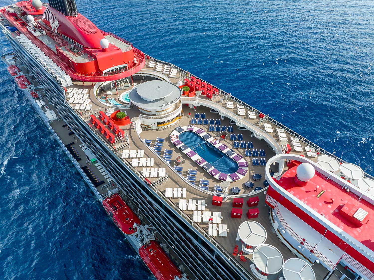 An aerial view of one of the pools and top deck seating on the Virgin Voyages Valiant Lady.