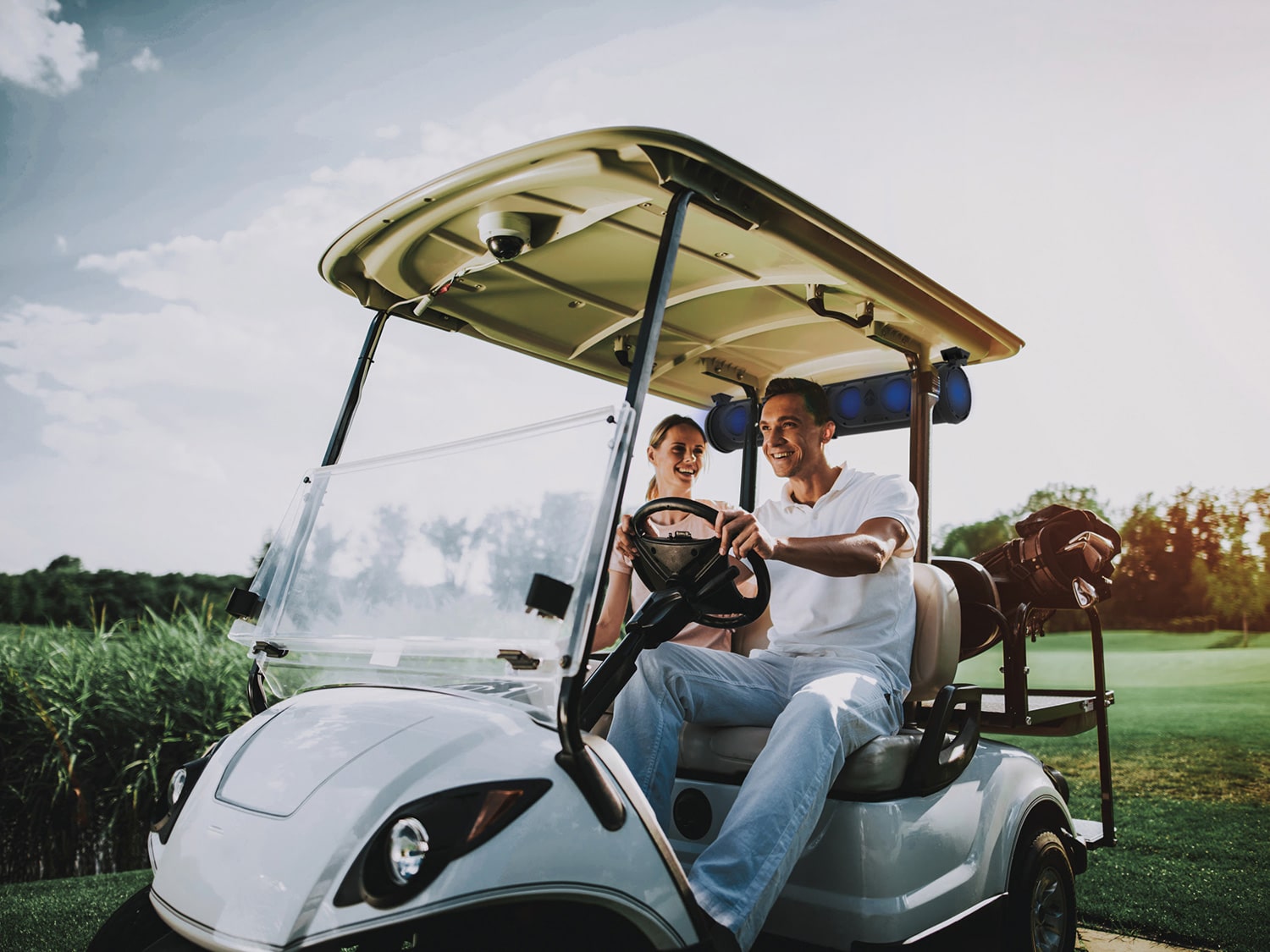 A couple in a golf cart listening to music on their SoundExtreme by ECOXGEAR wireless sound bar.