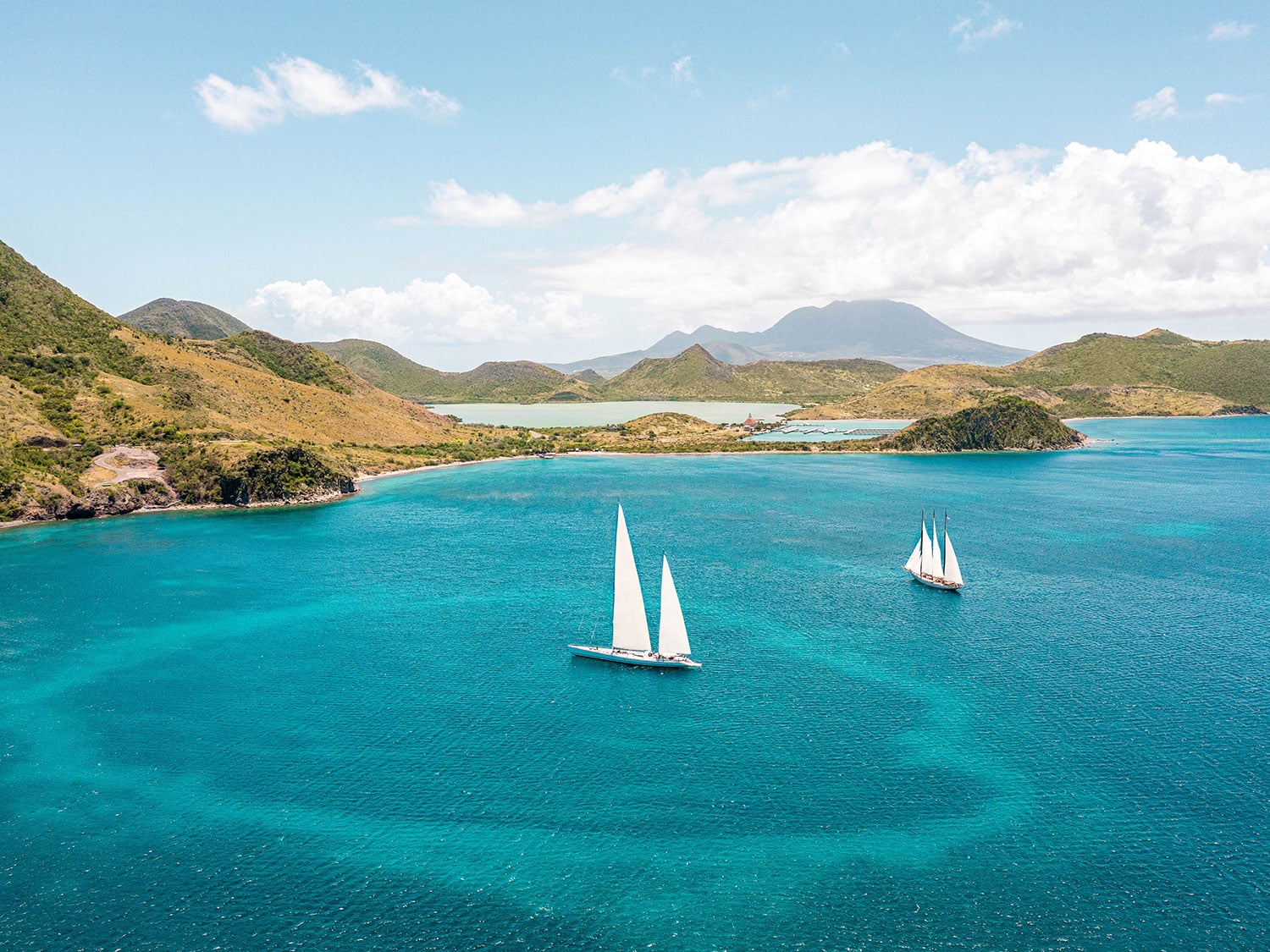 An aerial view of two boats in a bay in St. Kitts, surrounded by the island’s many hills.