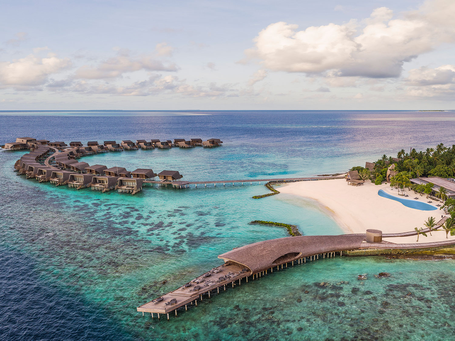 An aerial view of The St. Regis Maldives Vommuli Resort, with overwater bungalows and its iconic Whale Bar.