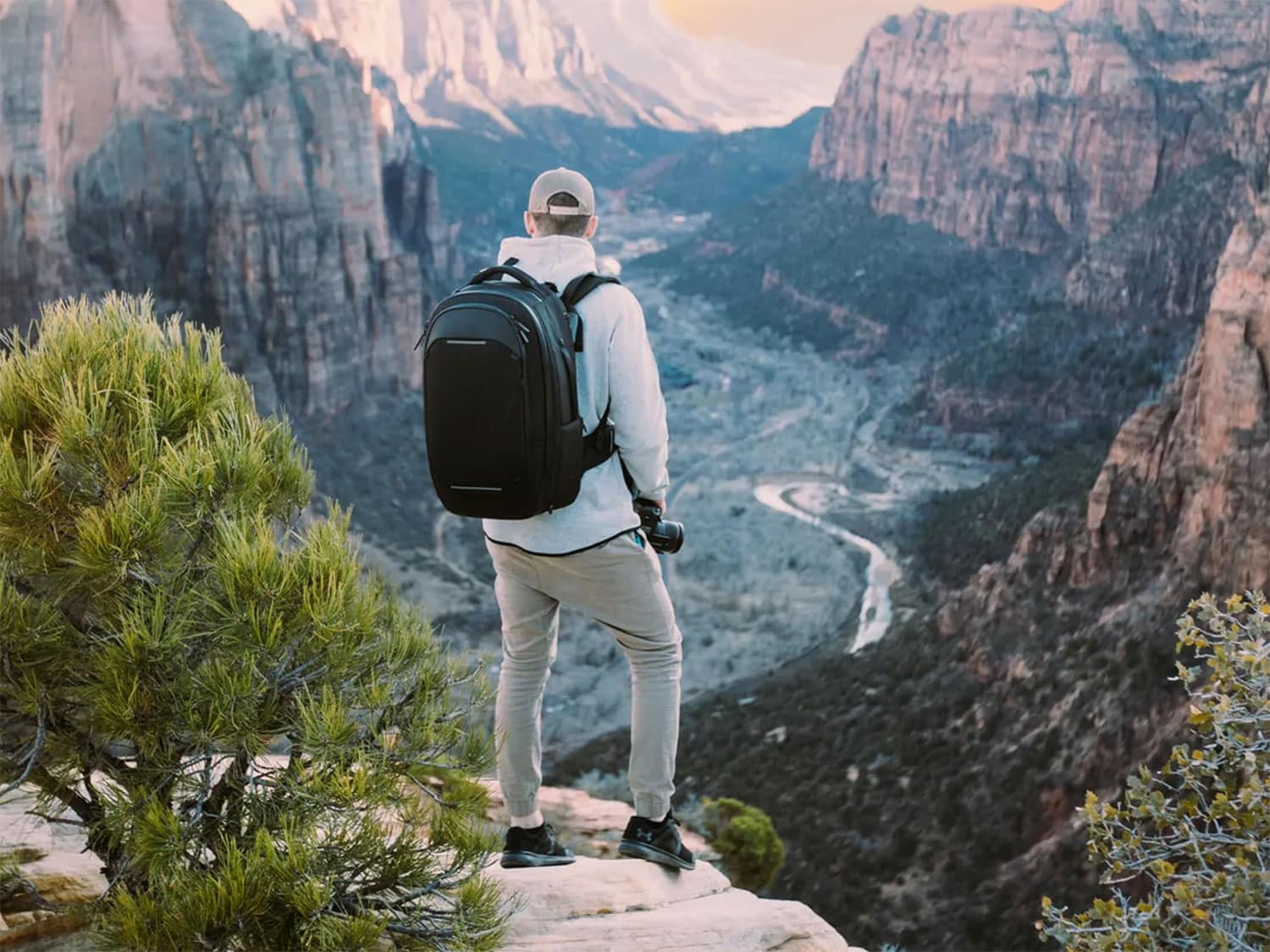 A male traveler admires scenery while wearing the Nomatic Navigator Travel Backpack 32L.
