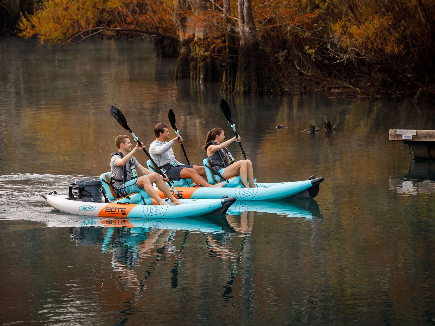 Three people paddling the Bote Zeppelin Aero Kayaks on a river.