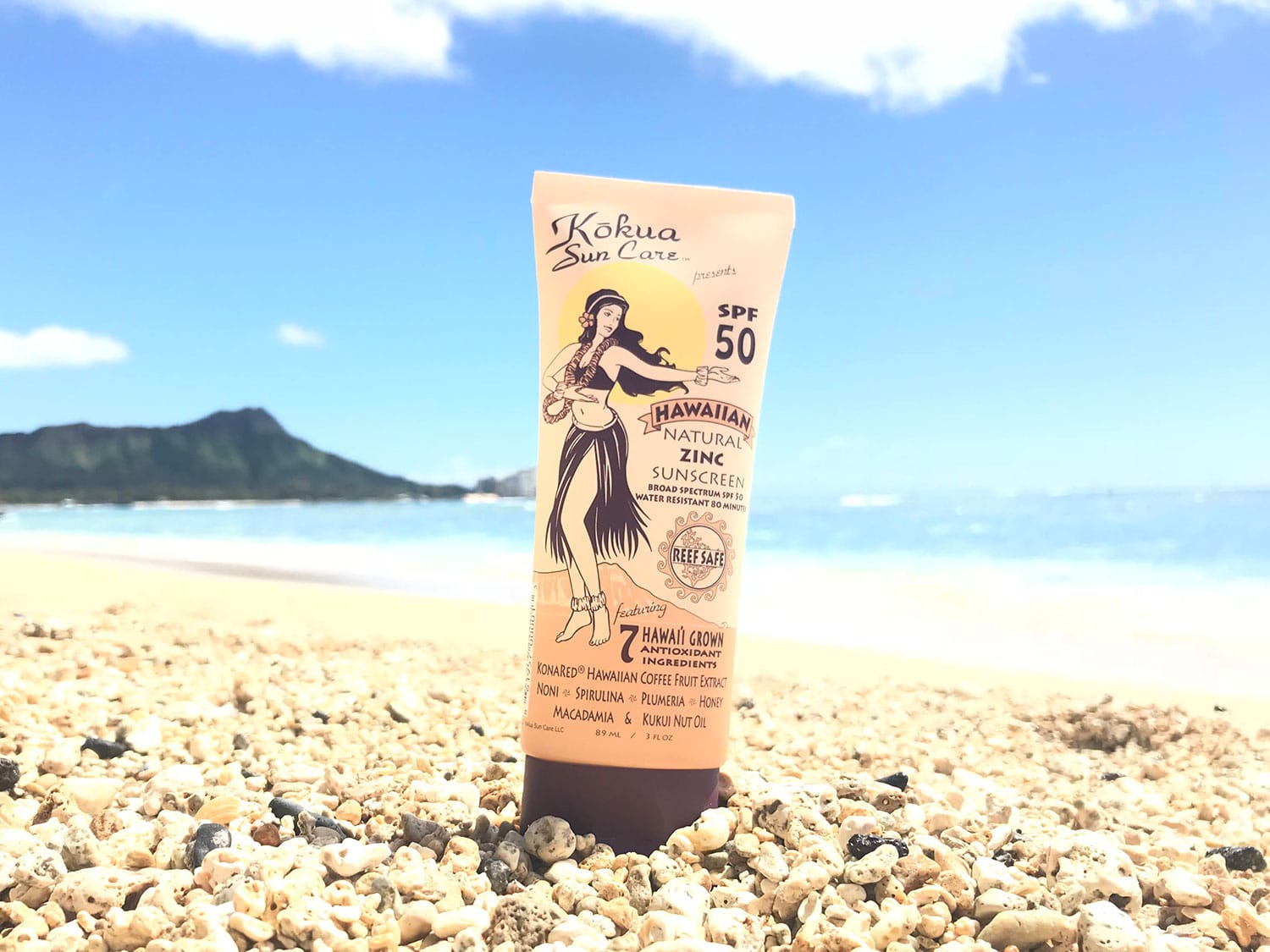 A bottle of Kōkua Sun Care Hawaiian Natural Zinc Sunscreen on the beach.