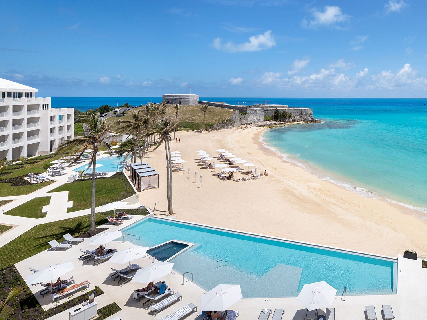 The pools and beach at The St. Regis Bermuda Resort with Fort St. Catherine in the distance.