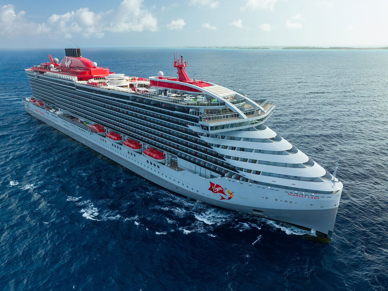 An aerial view of the Virgin Voyages Scarlet Lady cruise ship in the open waters.