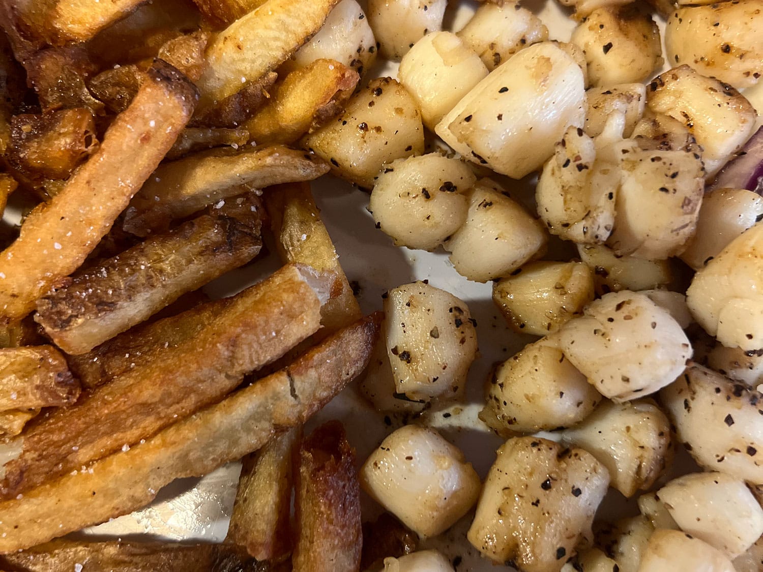 A serving of cooked scallops and fries.