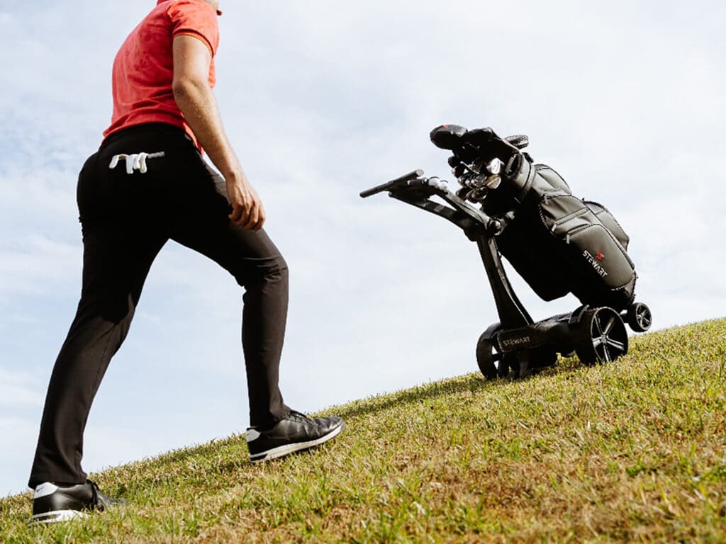 A golfer with the Stewart Golf VERTX Remote Trolley.