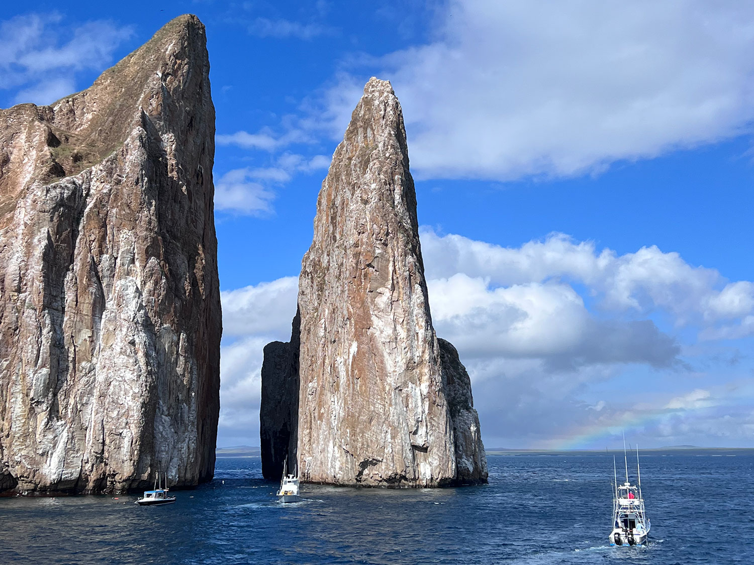 Boats in the waters around some rock formations in the Galapagos Islands.